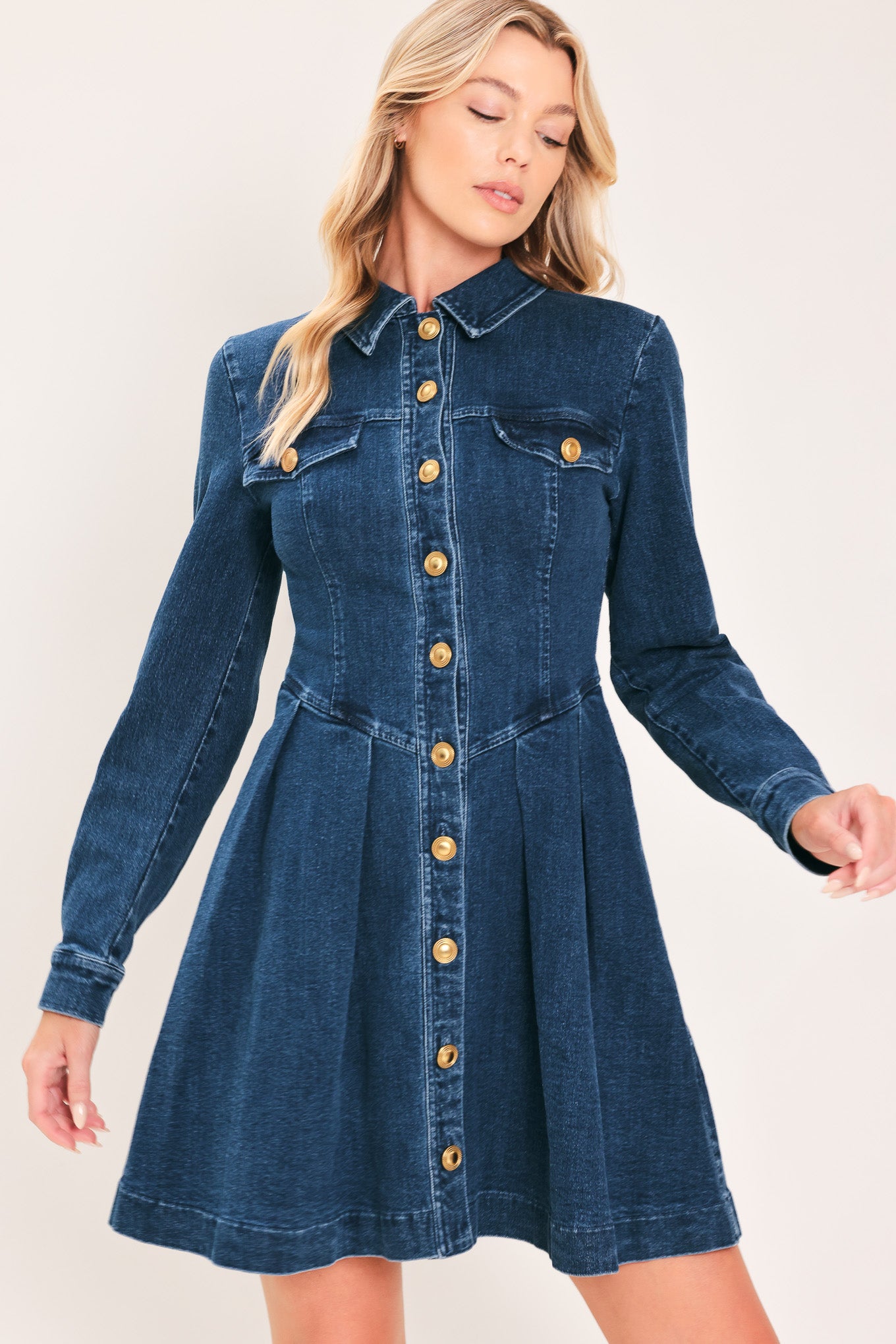 A woman modeling a blue denim long-sleeve shirt dress with gold-tone buttons | Flying Tomato