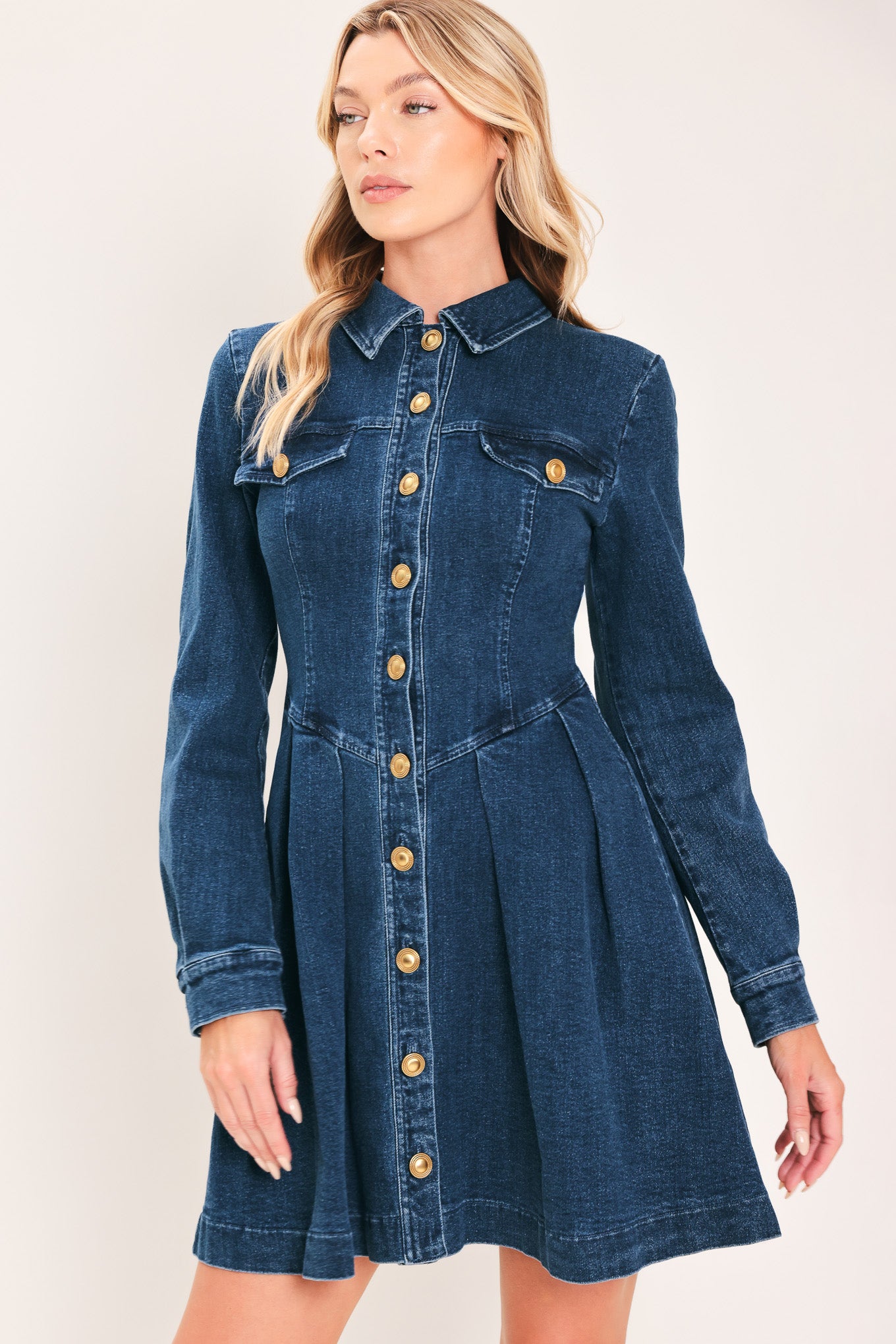 A woman modeling a blue denim long-sleeve shirt dress with gold-tone buttons | Flying Tomato