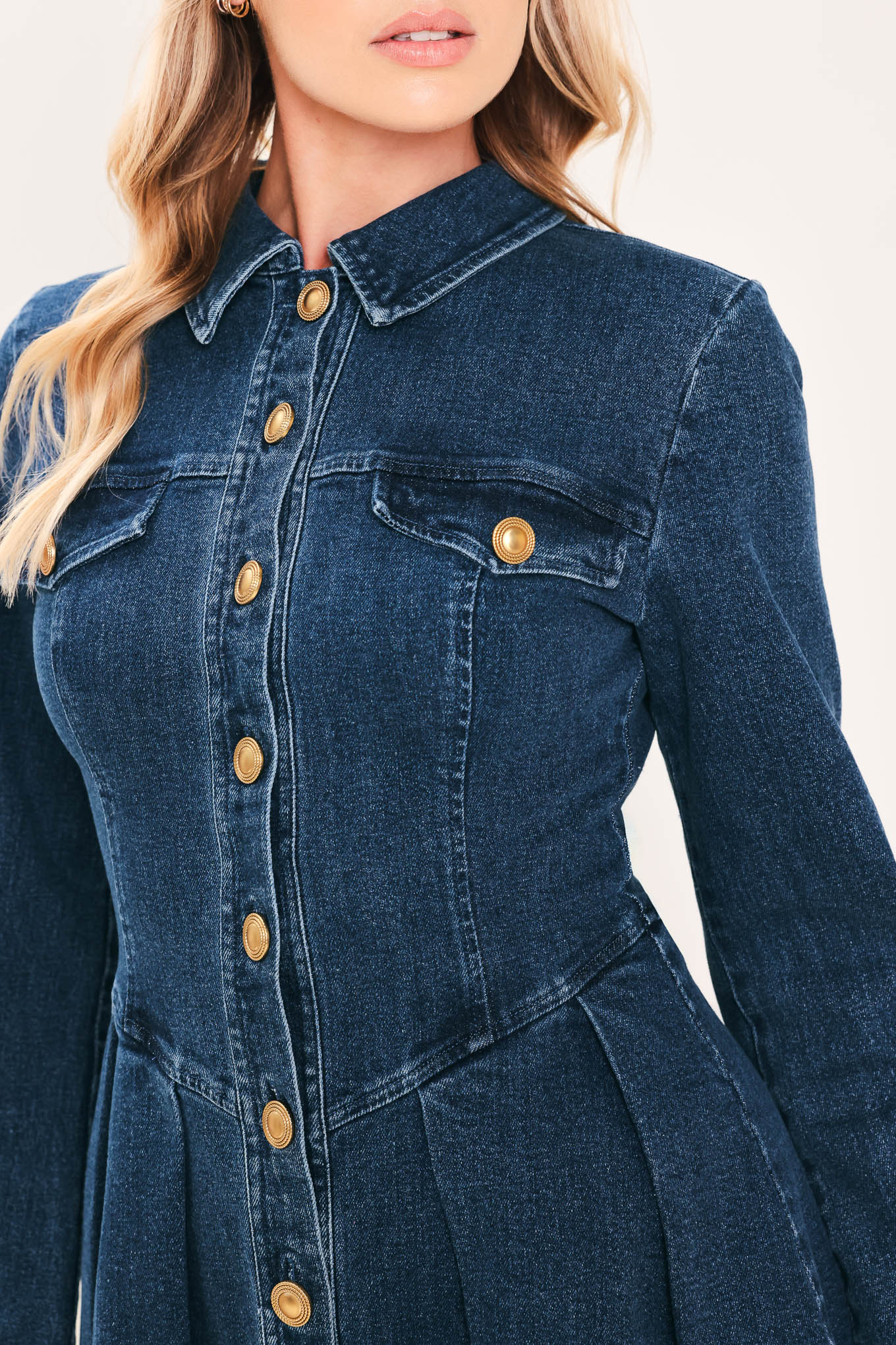 A woman modeling a blue denim long-sleeve shirt dress with gold-tone buttons | Flying Tomato