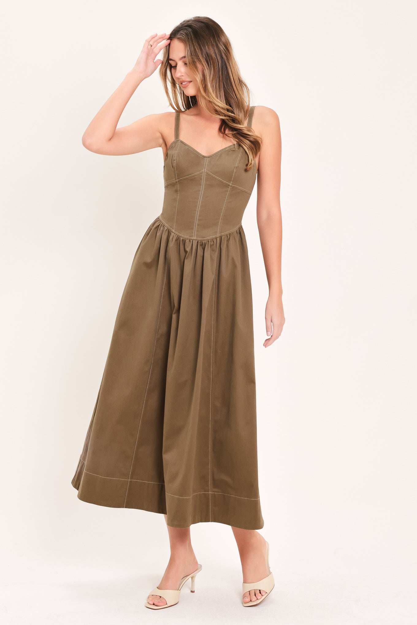 Woman wearing a cool tone brown sleeveless midi dress with bustier stitching details and princess cut waistline | Flying Tomato