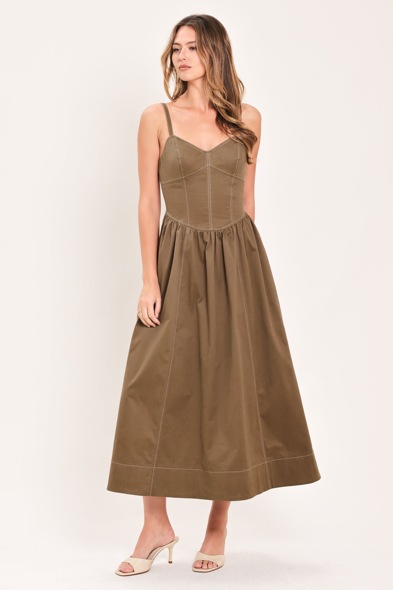 Woman wearing a cool tone brown sleeveless midi dress with bustier stitching details and princess cut waistline | Flying Tomato