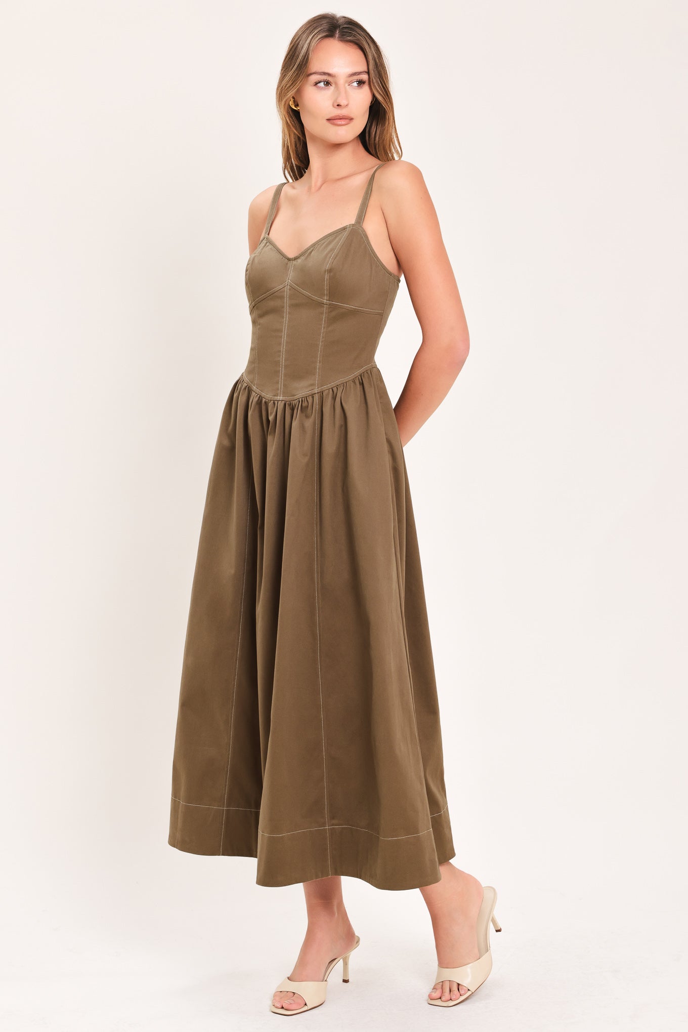 Woman wearing a cool tone brown sleeveless midi dress with bustier stitching details and princess cut waistline | Flying Tomato