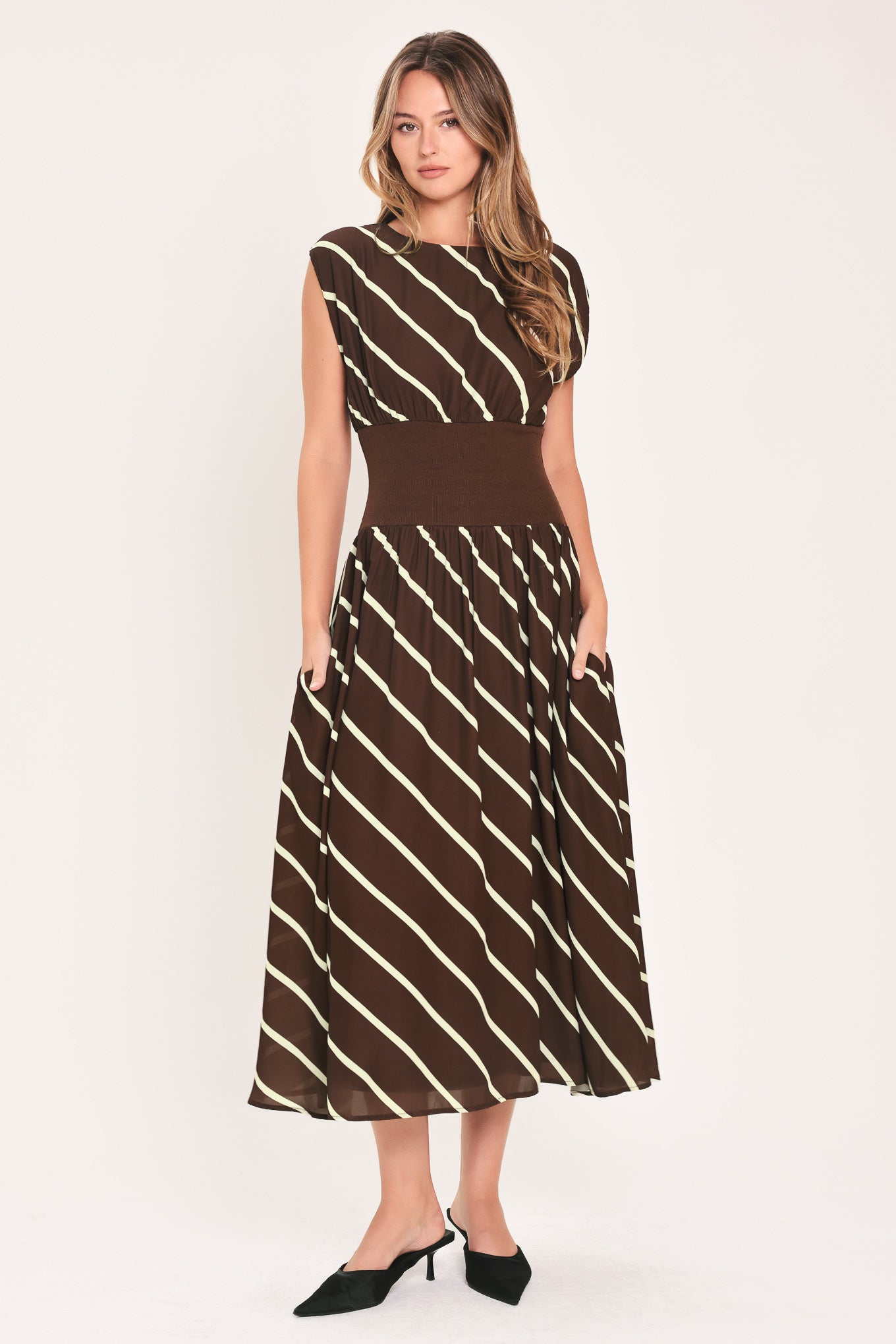 A woman modeling a sleeveless midi dress with a brown and cream diagonal striped pattern, featuring a defined waistband | Flying Tomato