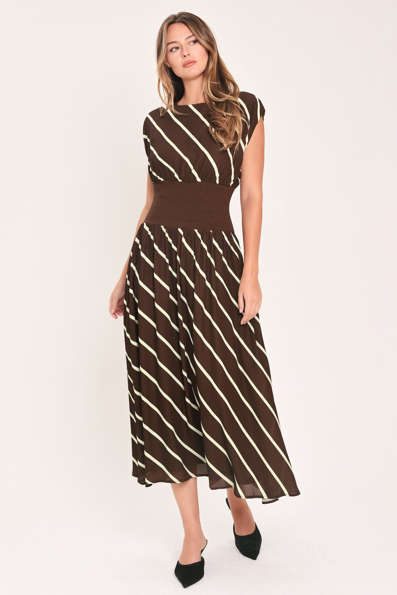 A woman modeling a sleeveless midi dress with a brown and cream diagonal striped pattern, featuring a defined waistband | Flying Tomato