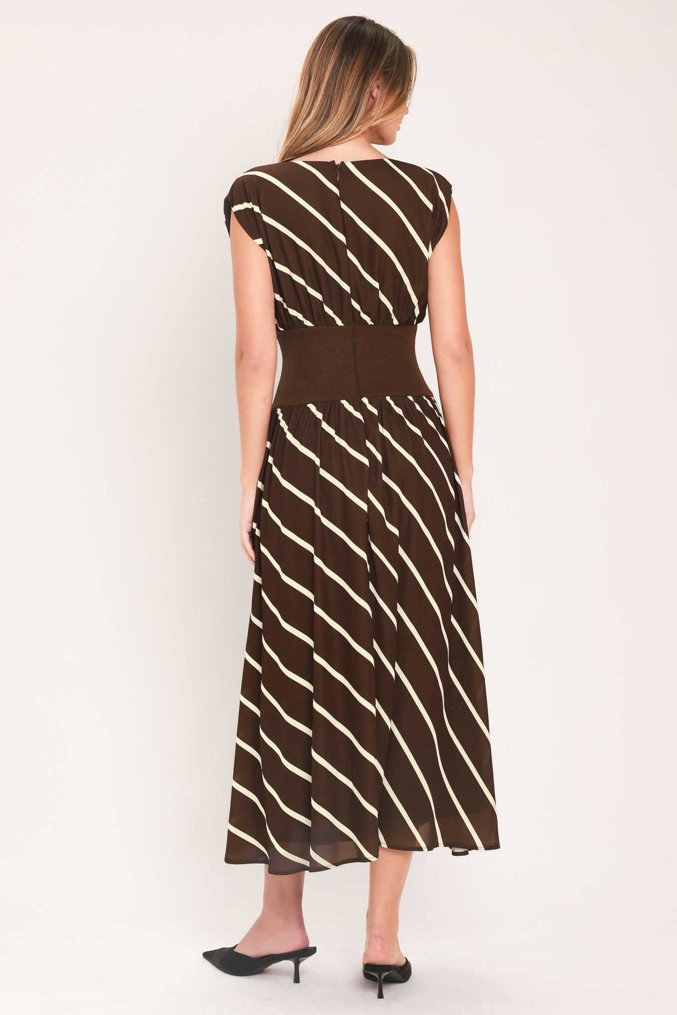 A woman modeling a sleeveless midi dress with a brown and cream diagonal striped pattern, featuring a defined waistband | Flying Tomato