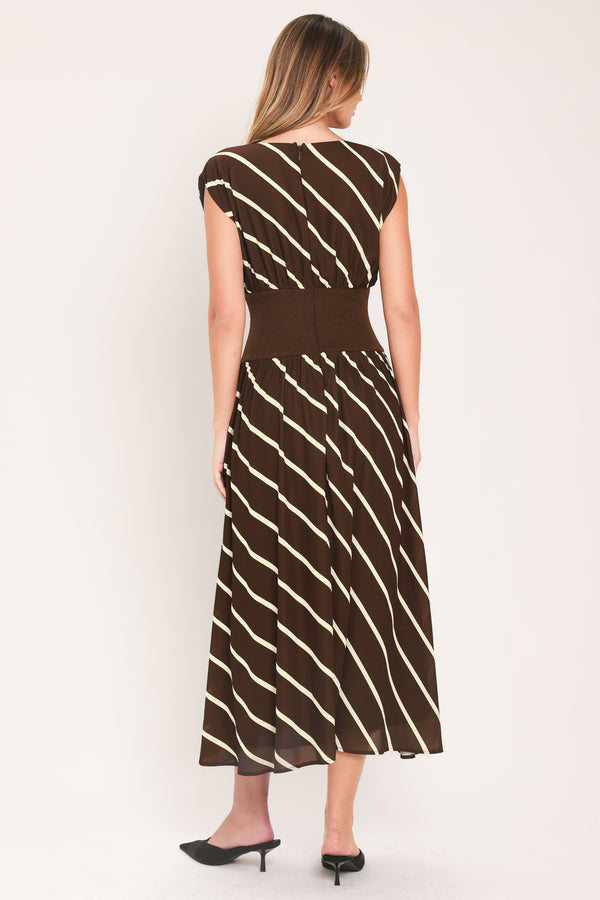 A woman modeling a sleeveless midi dress with a brown and cream diagonal striped pattern, featuring a defined waistband | Flying Tomato