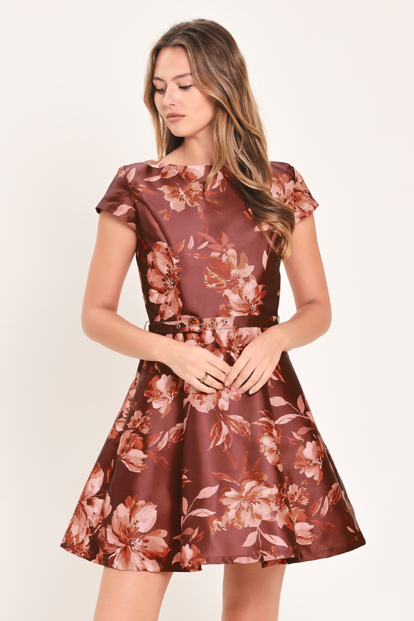 A woman modeling a short-sleeve fit-and-flare dress with a burgundy satin-like base and a pink floral pattern | Flying Tomato