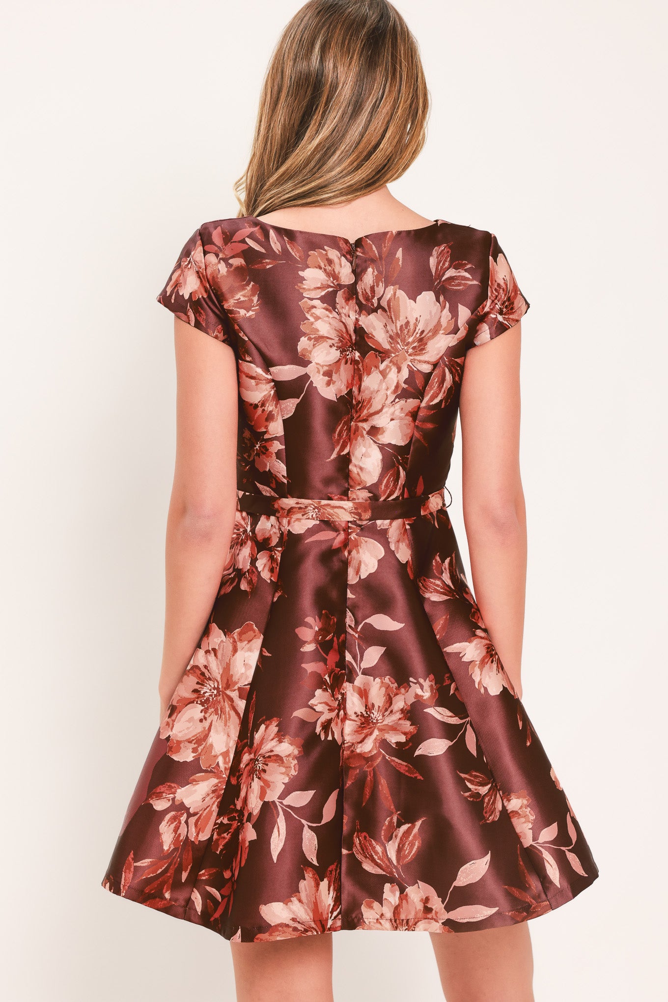 A woman modeling a short-sleeve fit-and-flare dress with a burgundy satin-like base and a pink floral pattern | Flying Tomato