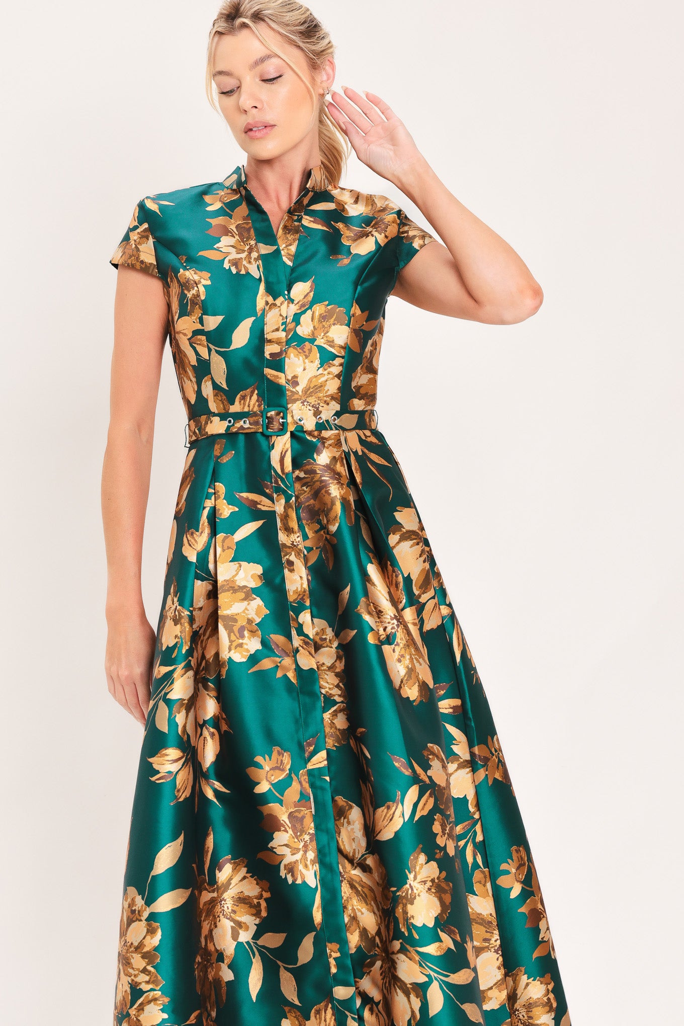 A woman modeling a maxi green satin dress with a gold floral print | Flying Tomato