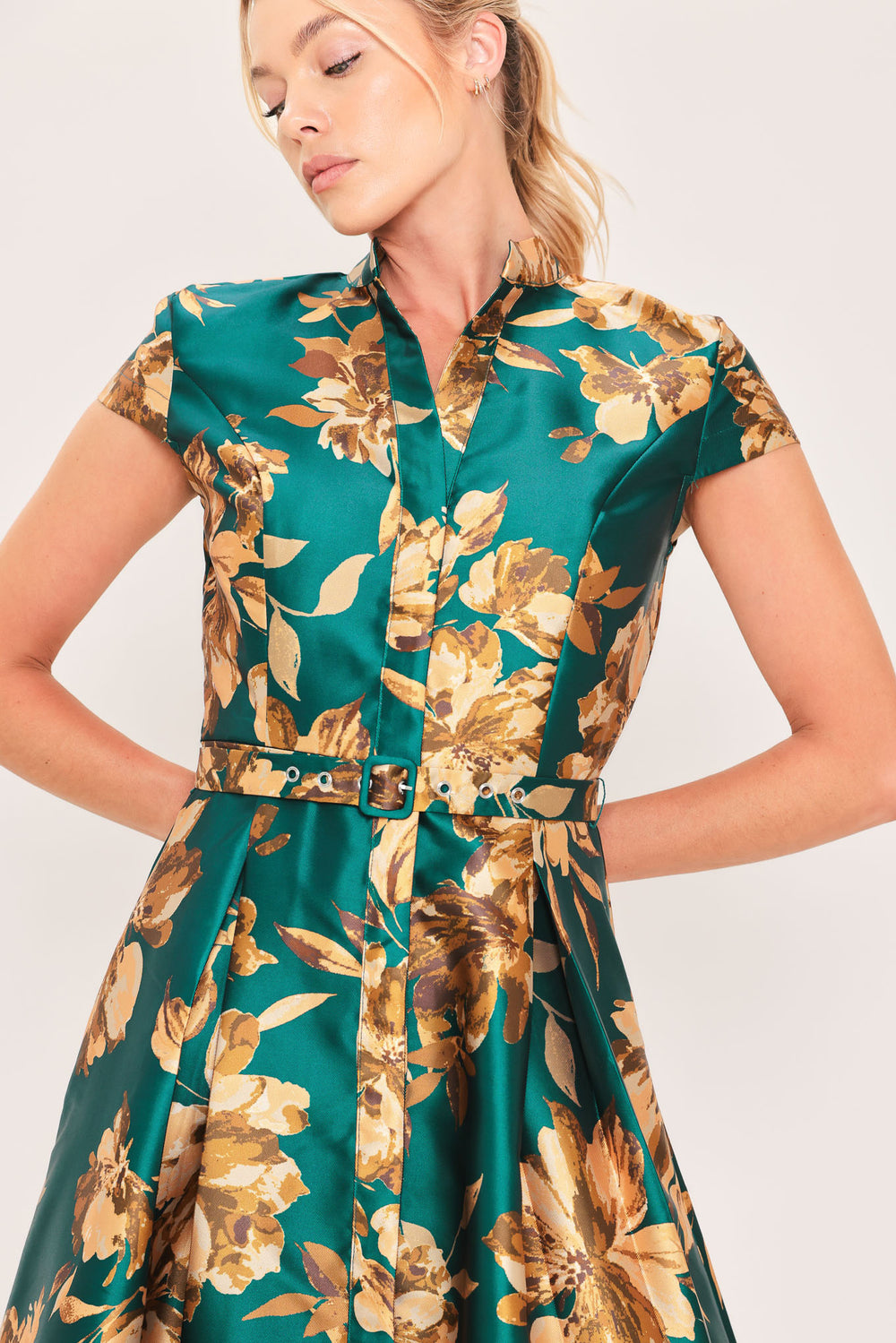 A woman modeling a maxi green satin dress with a gold floral print | Flying Tomato