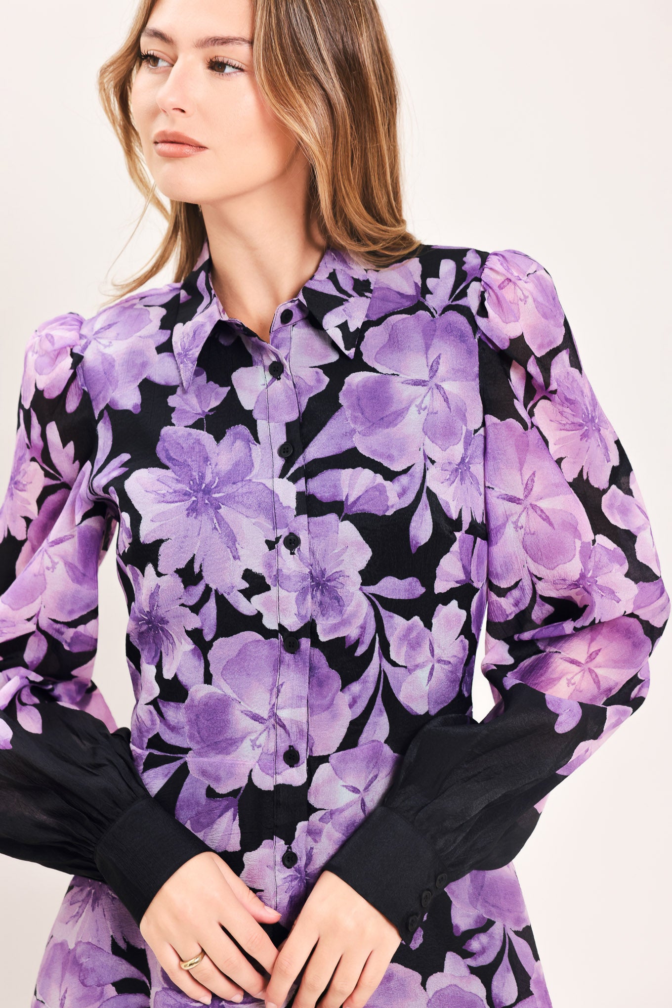 A woman modeling a long-sleeved maxi dress with a black base and a large purple floral print | Flying Tomato