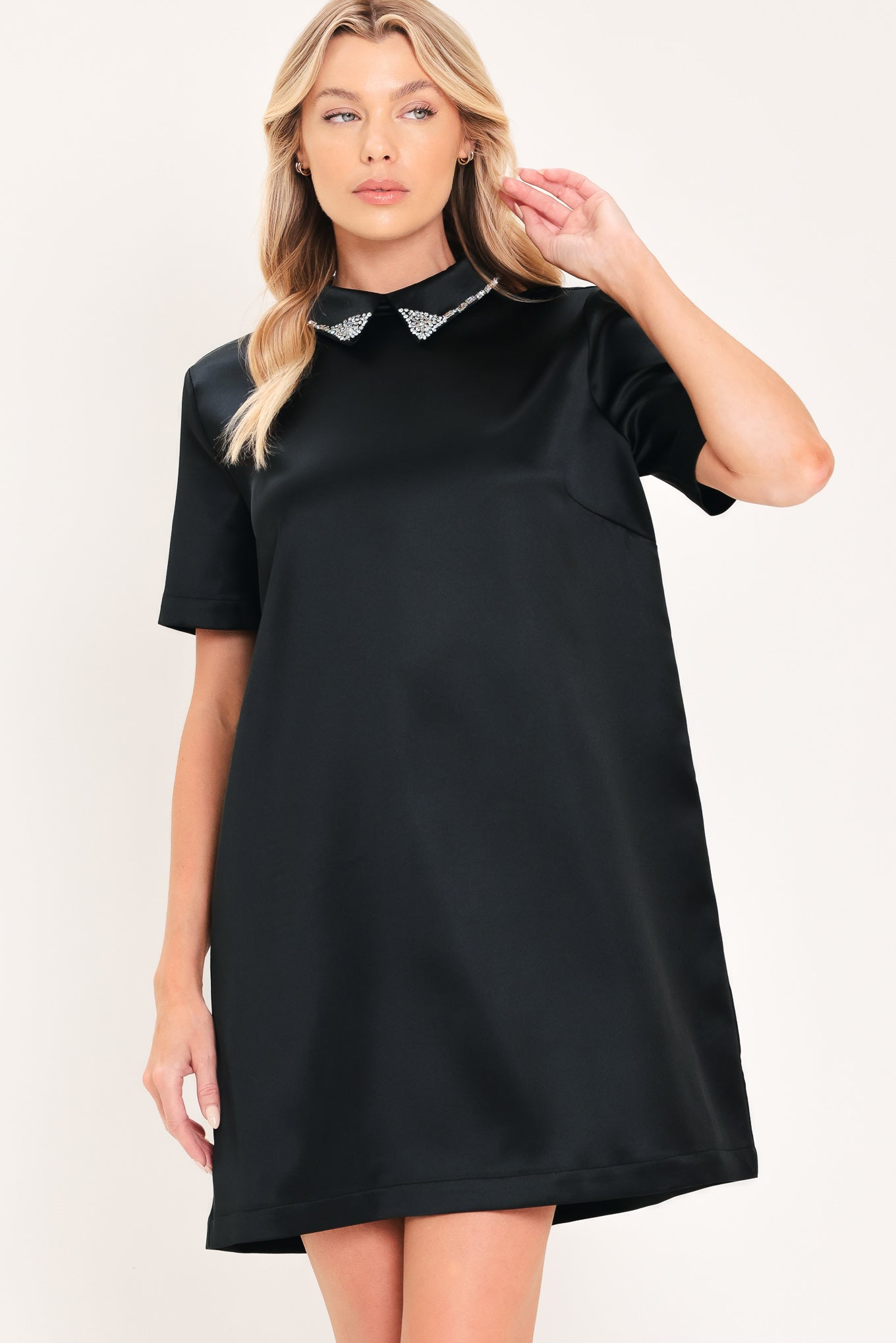 A woman modeling a black short-sleeve satin dress with a decorative silver collar | Flying Tomato