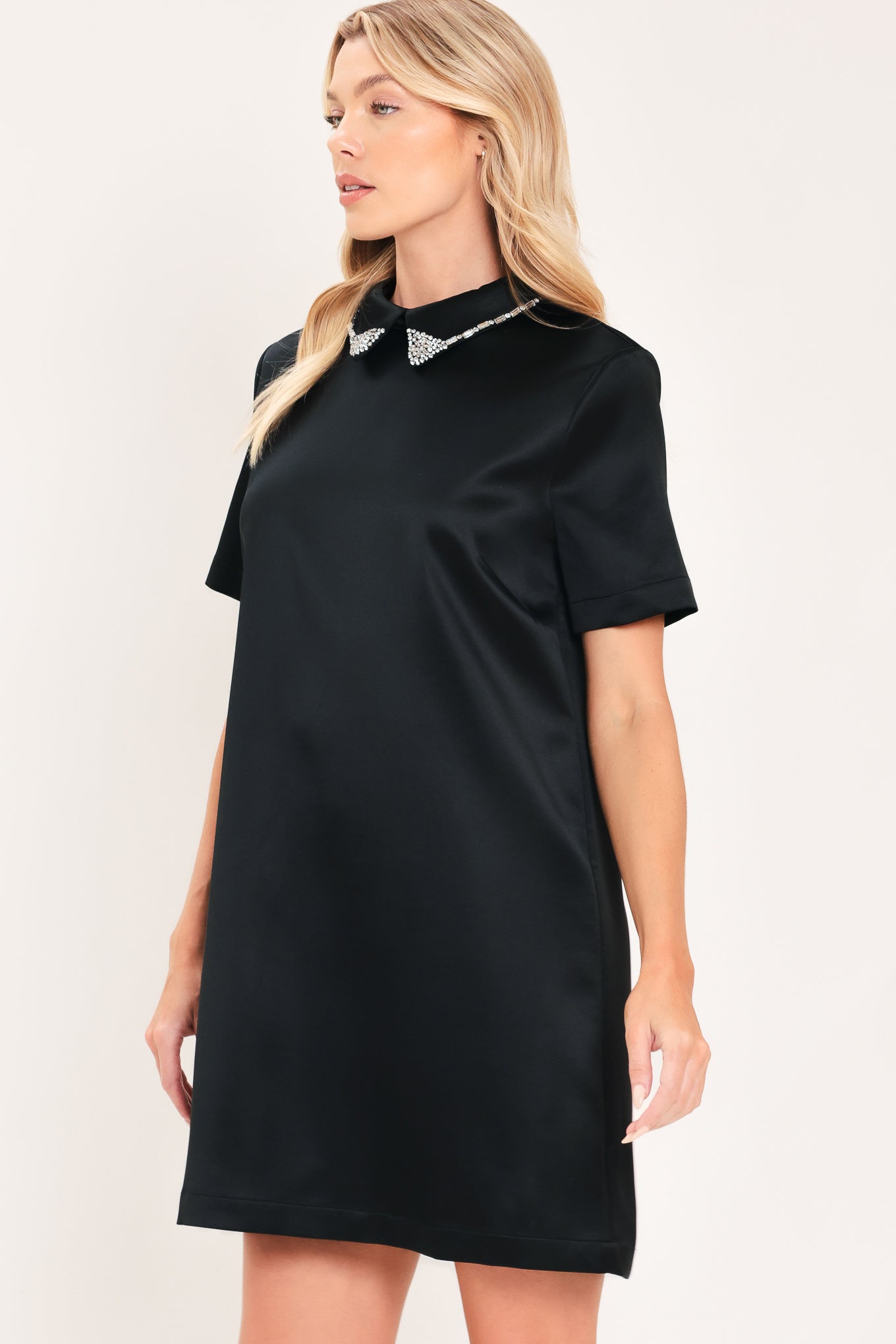 A woman modeling a black short-sleeve satin dress with a decorative silver collar | Flying Tomato