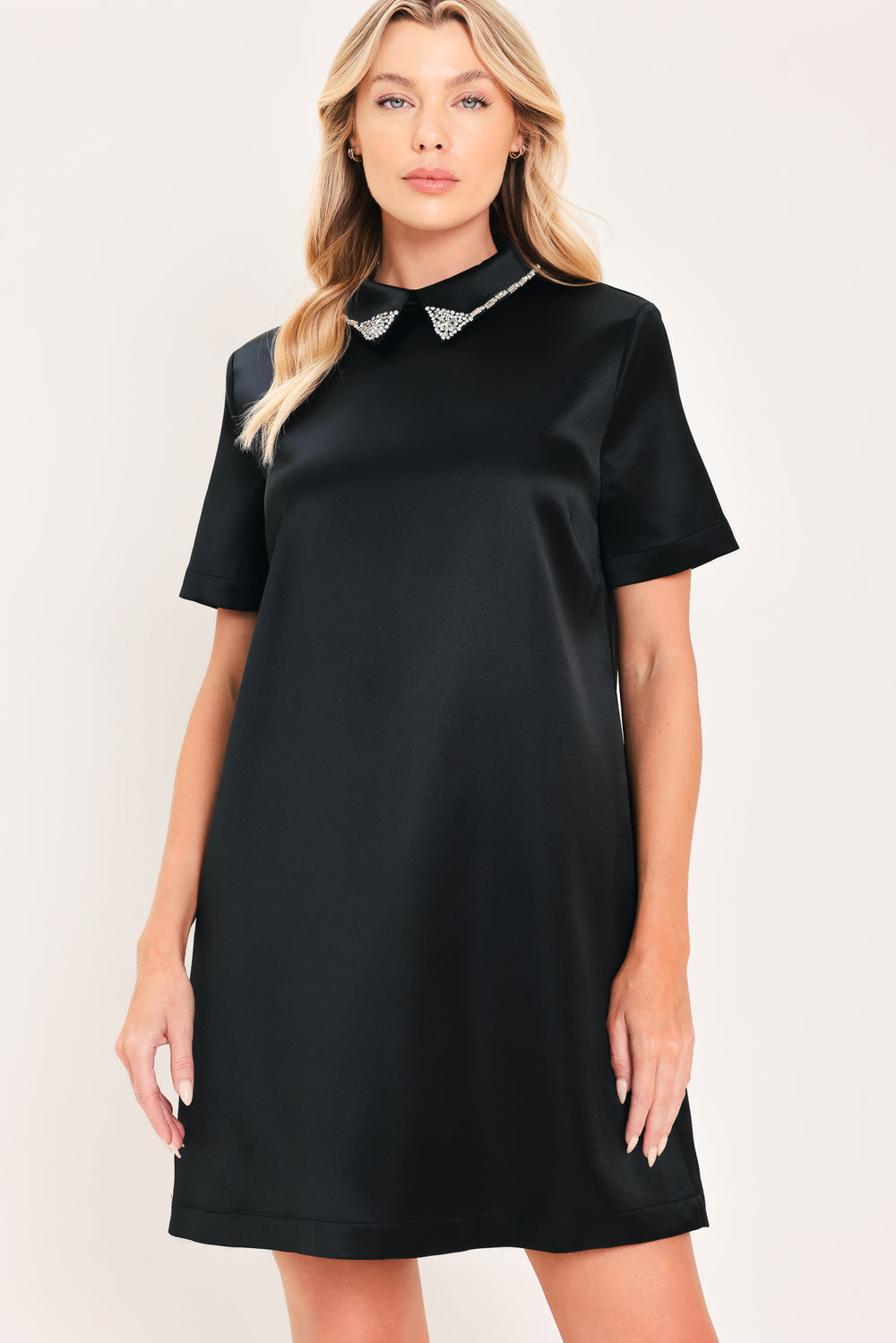 A woman modeling a black short-sleeve satin dress with a decorative silver collar | Flying Tomato