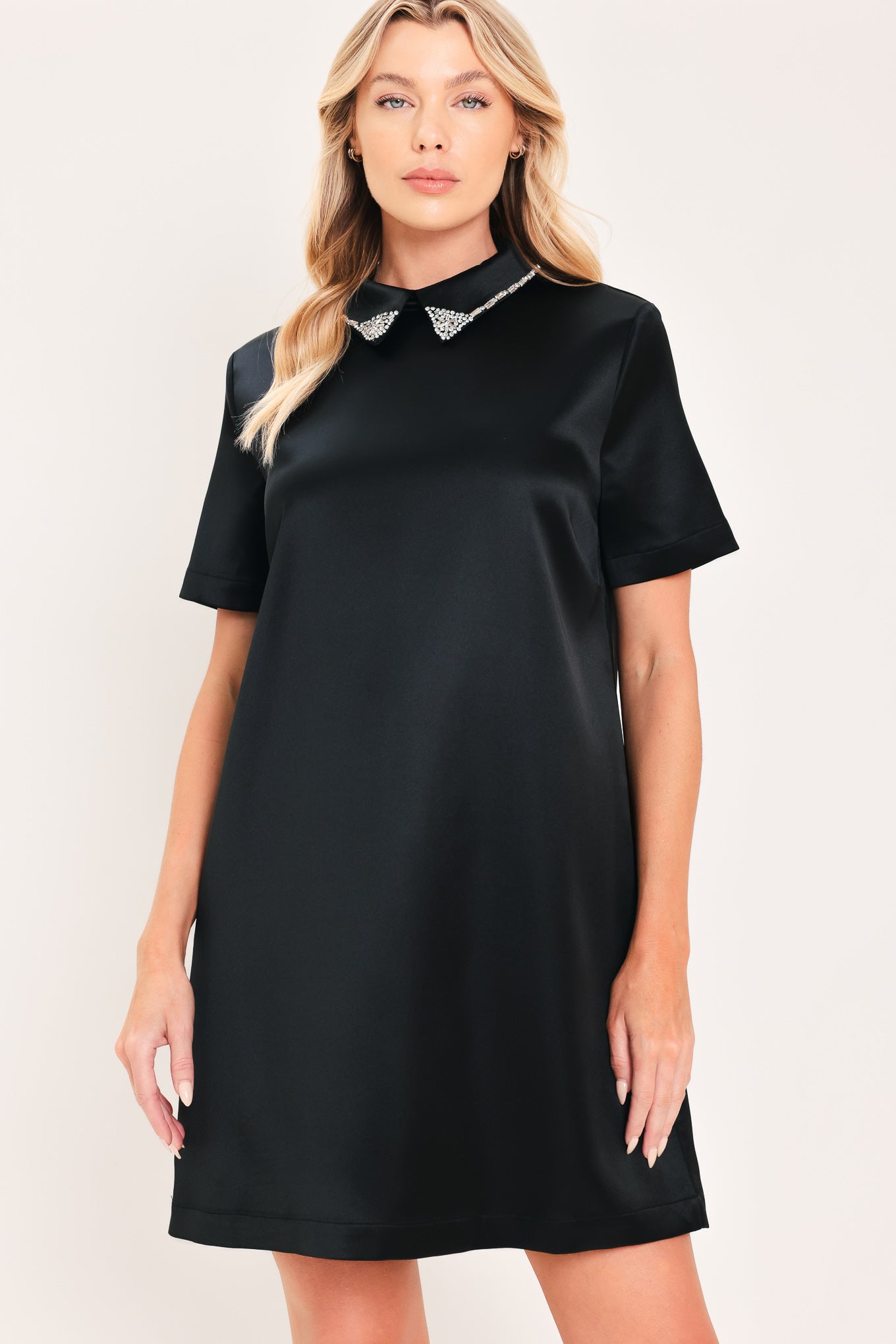A woman modeling a black short-sleeve satin dress with a decorative silver collar | Flying Tomato
