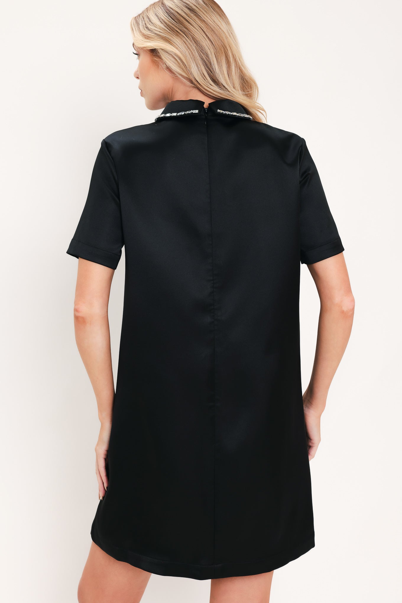 A woman modeling a black short-sleeve satin dress with a decorative silver collar | Flying Tomato