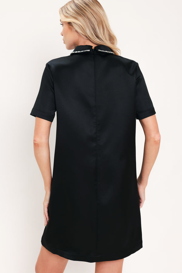 A woman modeling a black short-sleeve satin dress with a decorative silver collar | Flying Tomato
