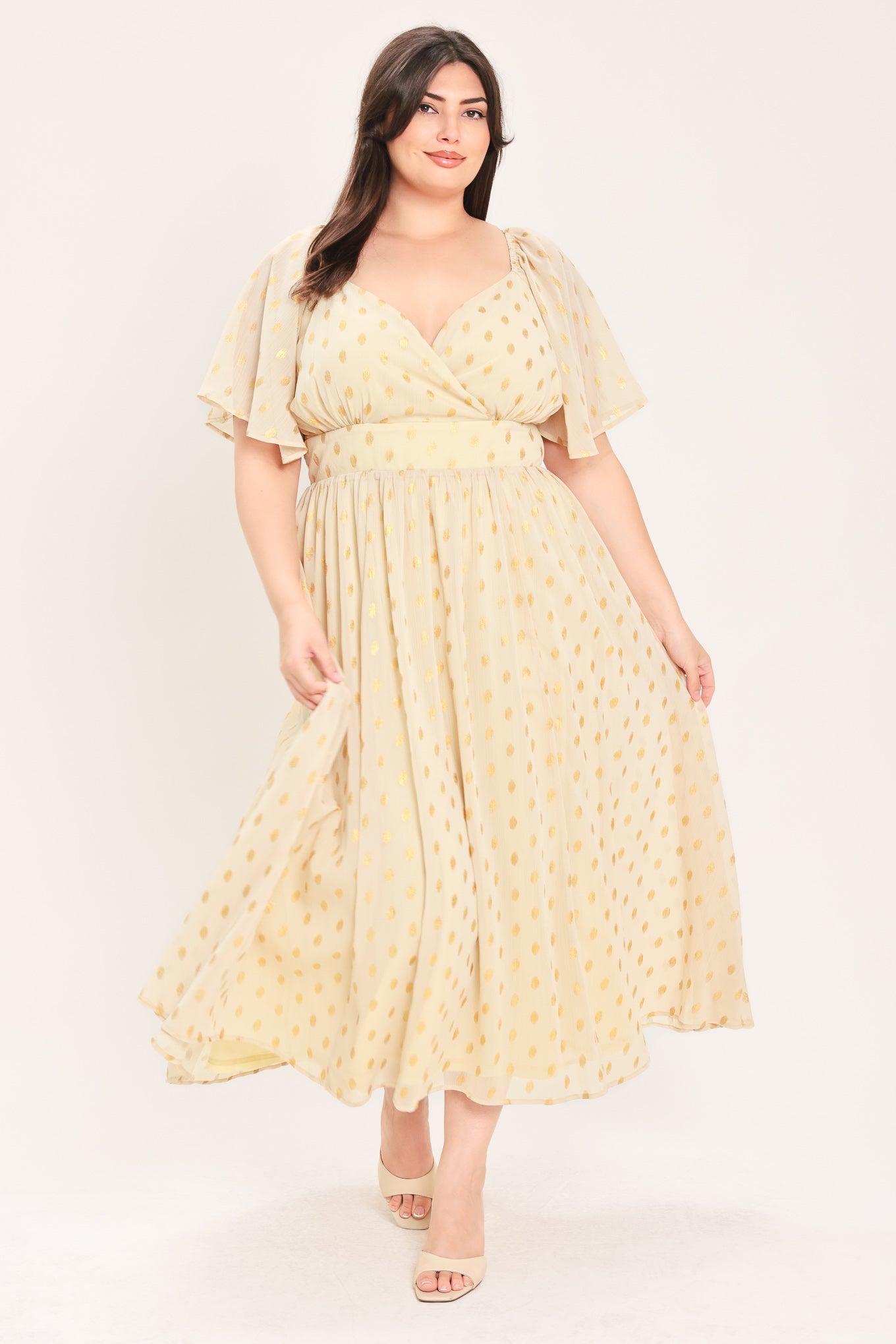 A woman modeling a light yellow midi dress with a small gold dotted pattern, featuring flutter sleeves and a V-neckline | Flying Tomato Curve