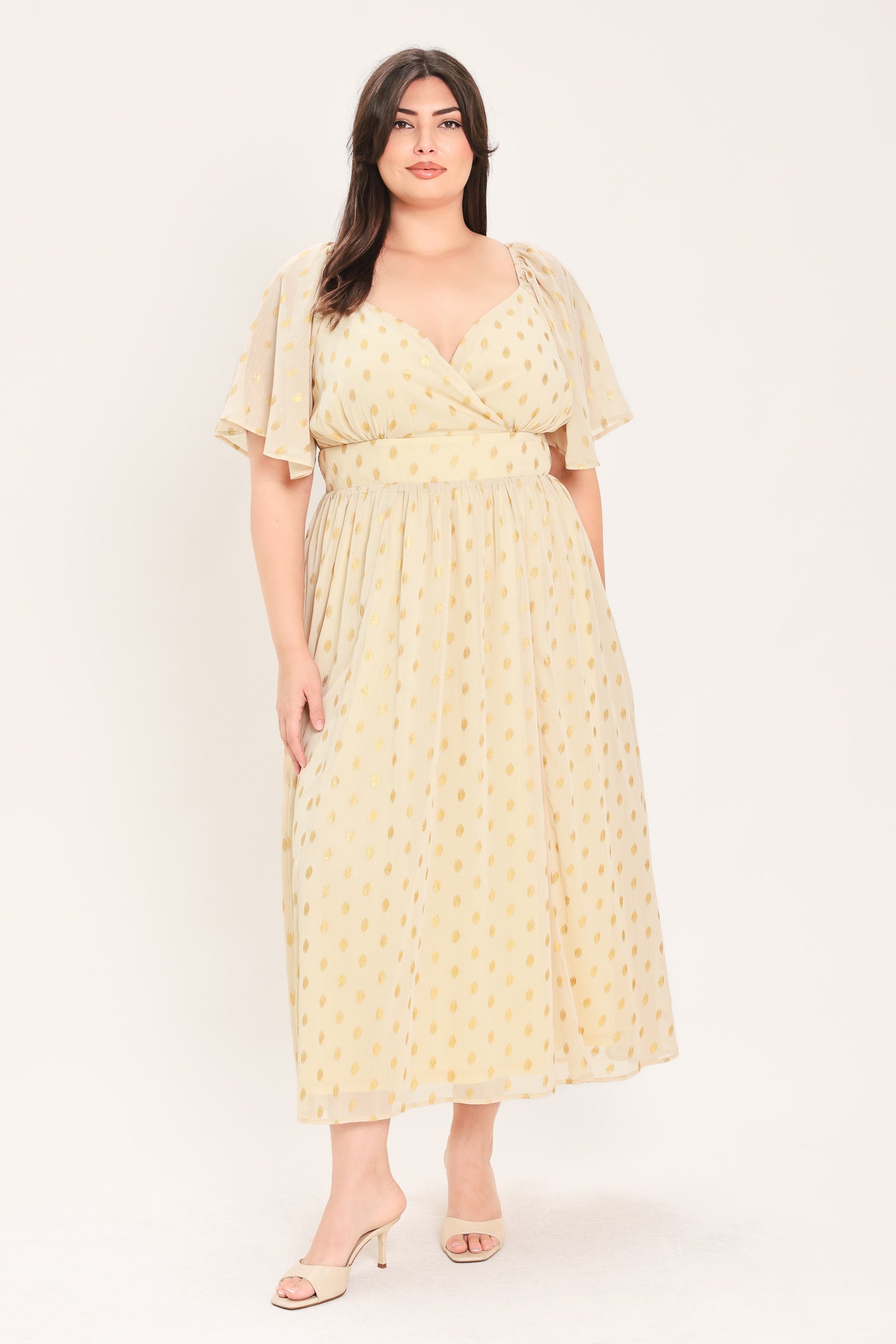 A woman modeling a light yellow midi dress with a small gold dotted pattern, featuring flutter sleeves and a V-neckline | Flying Tomato Curve