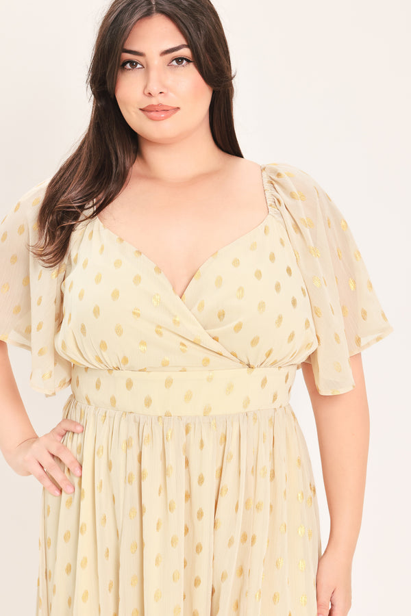A woman modeling a light yellow midi dress with a small gold dotted pattern, featuring flutter sleeves and a V-neckline | Flying Tomato Curve