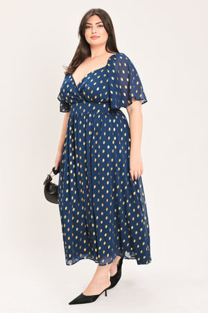 A woman modeling a light yellow midi dress with a small gold dotted pattern, featuring flutter sleeves and a V-neckline | Flying Tomato Curve