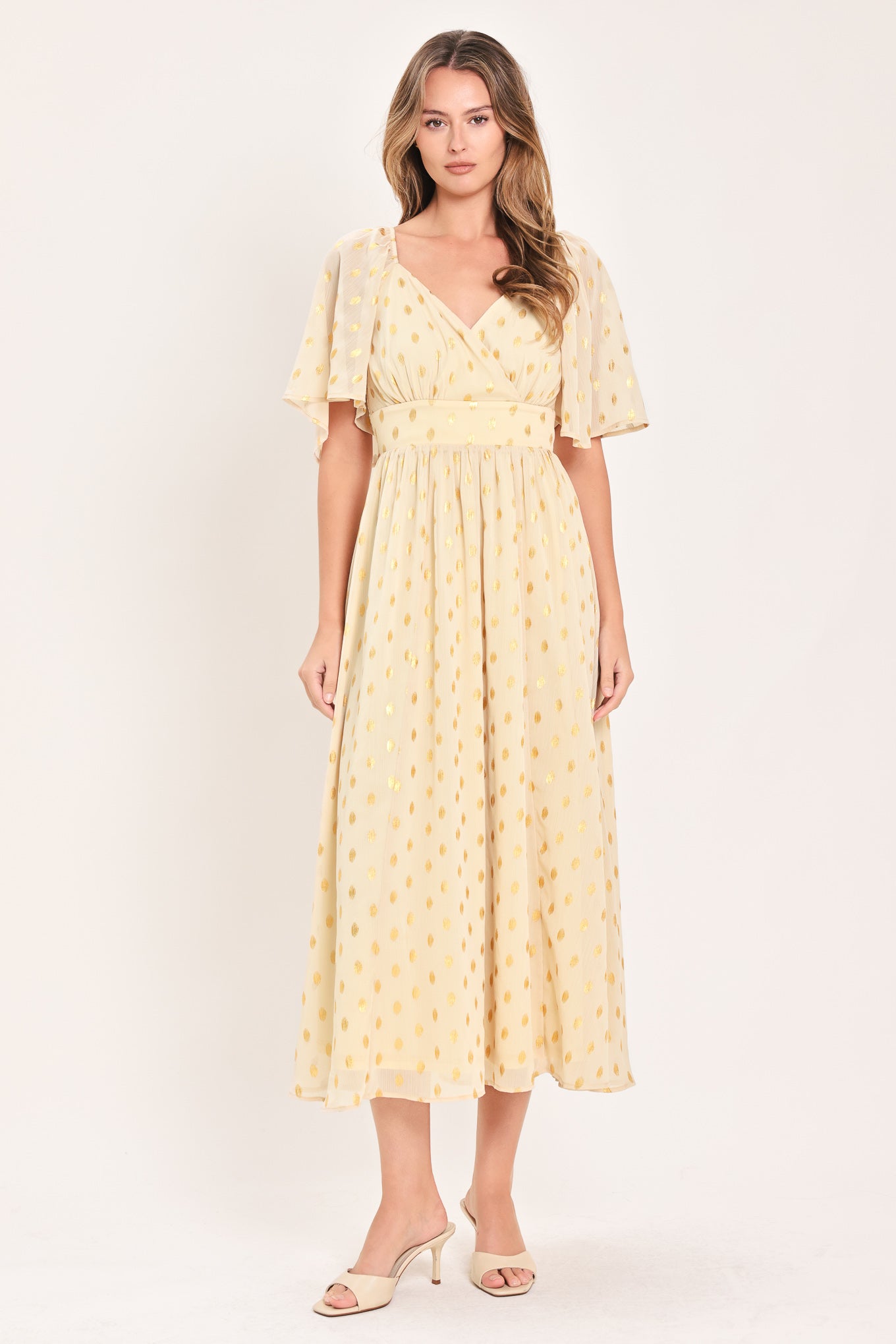 A woman modeling a light yellow midi dress with a small gold dotted pattern, featuring flutter sleeves and a V-neckline | Flying Tomato