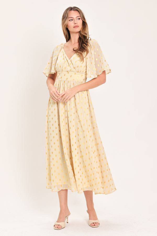 A woman modeling a light yellow midi dress with a small gold dotted pattern, featuring flutter sleeves and a V-neckline | Flying Tomato