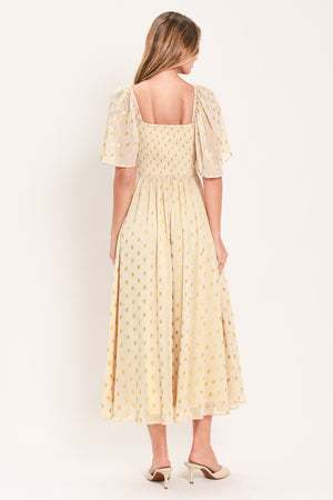 A woman modeling a light yellow midi dress with a small gold dotted pattern, featuring flutter sleeves and a V-neckline | Flying Tomato