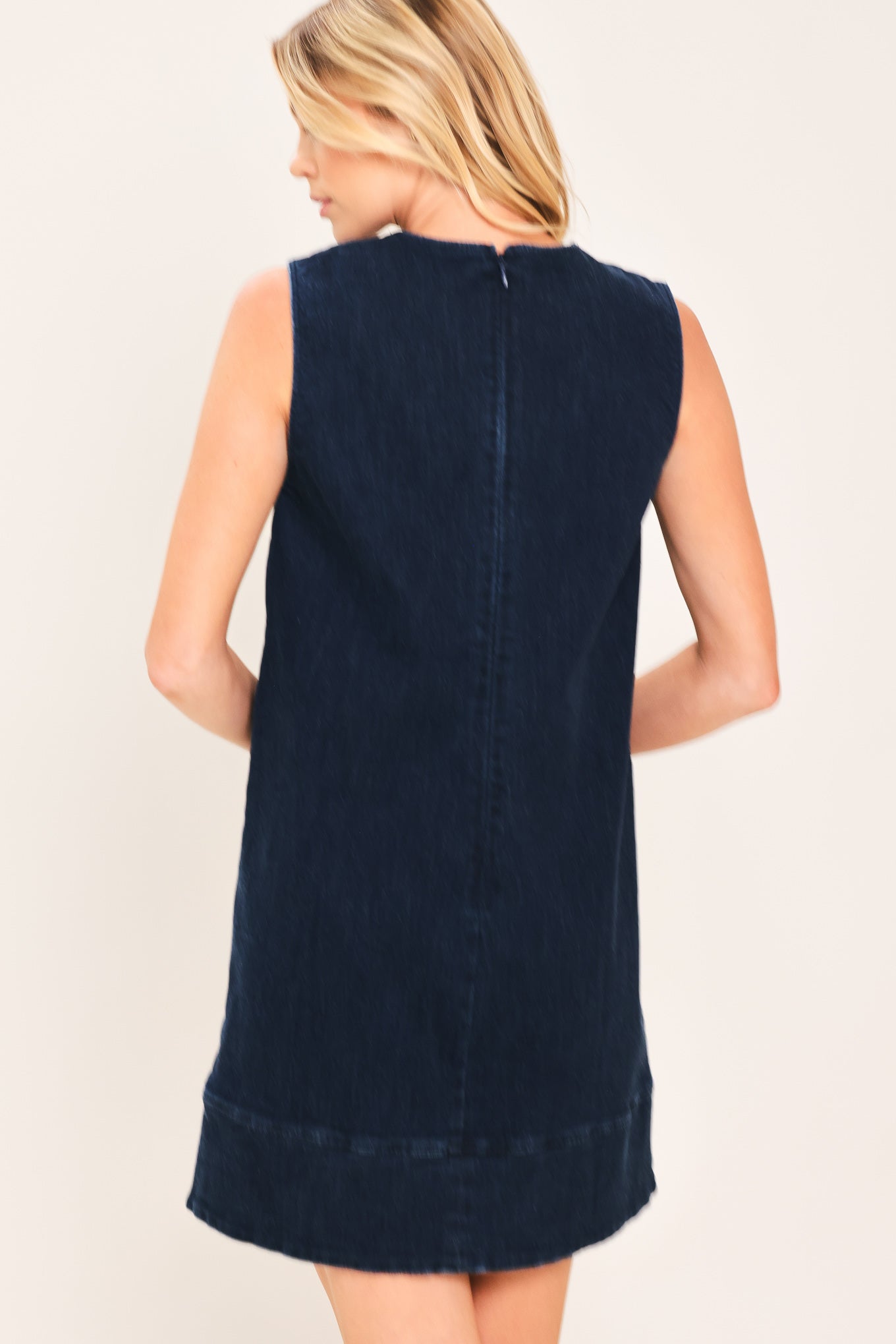 A woman wearing a sleeveless dark navy blue dress with a scalloped V-neckline | Flying Tomato