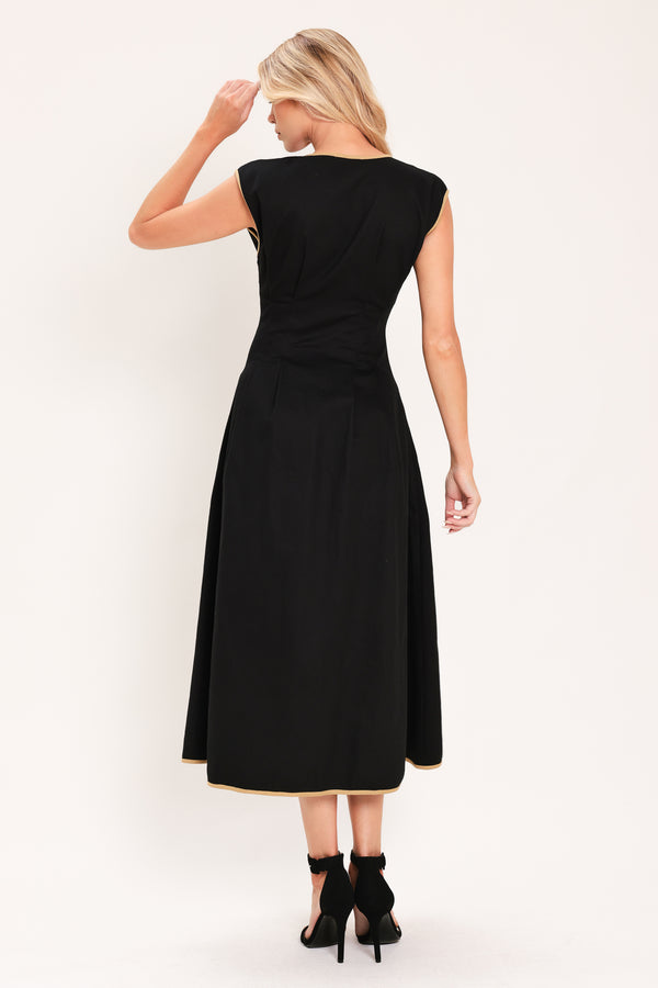 A woman modeling a sleeveless black midi dress with a V-neckline, front button placket, side pockets, and thin gold trim at the hem | Flying Tomato