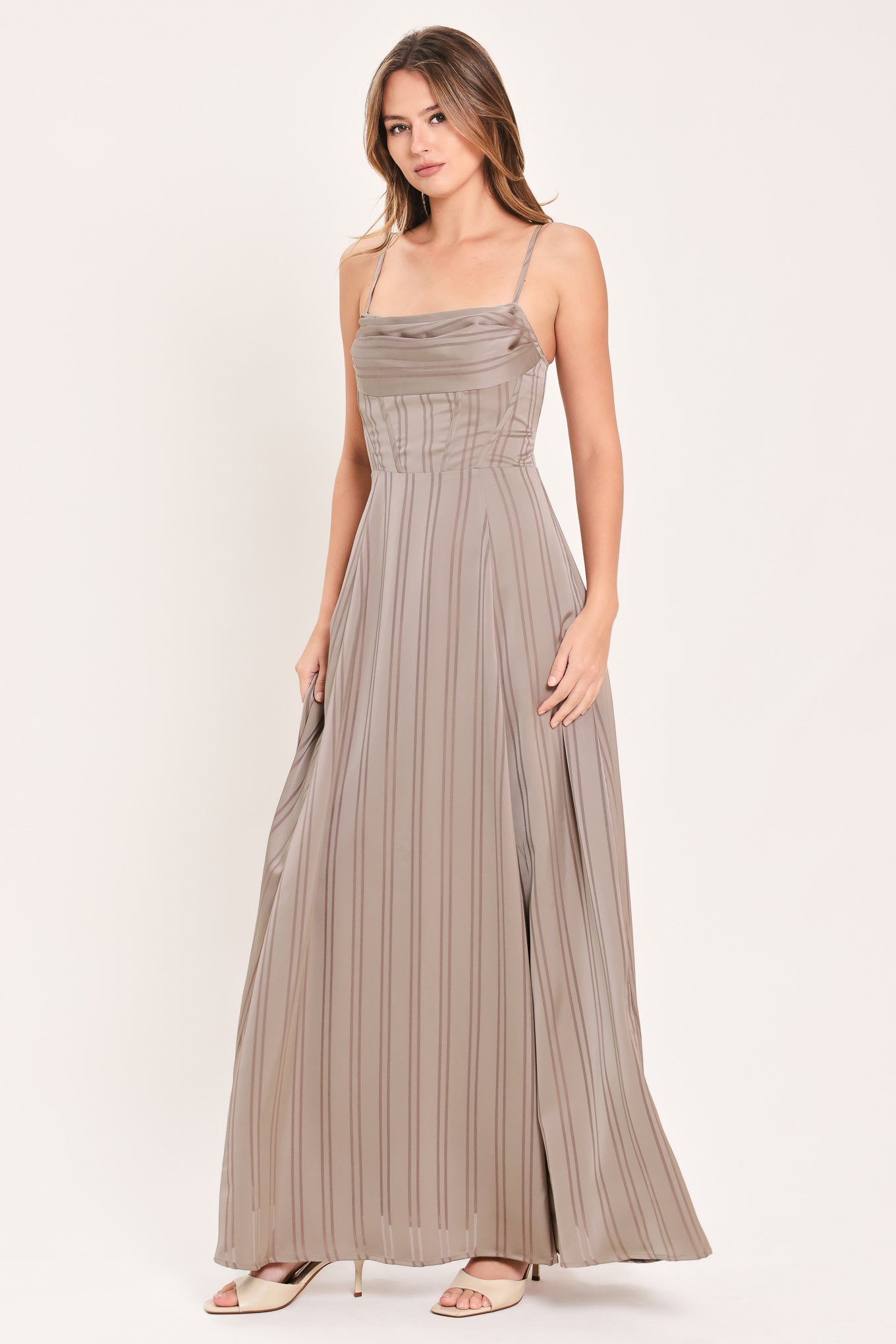 A woman modeling a floor-length taupe pleated maxi dress with spaghetti straps and a gathered sweetheart neckline | Flying Tomato