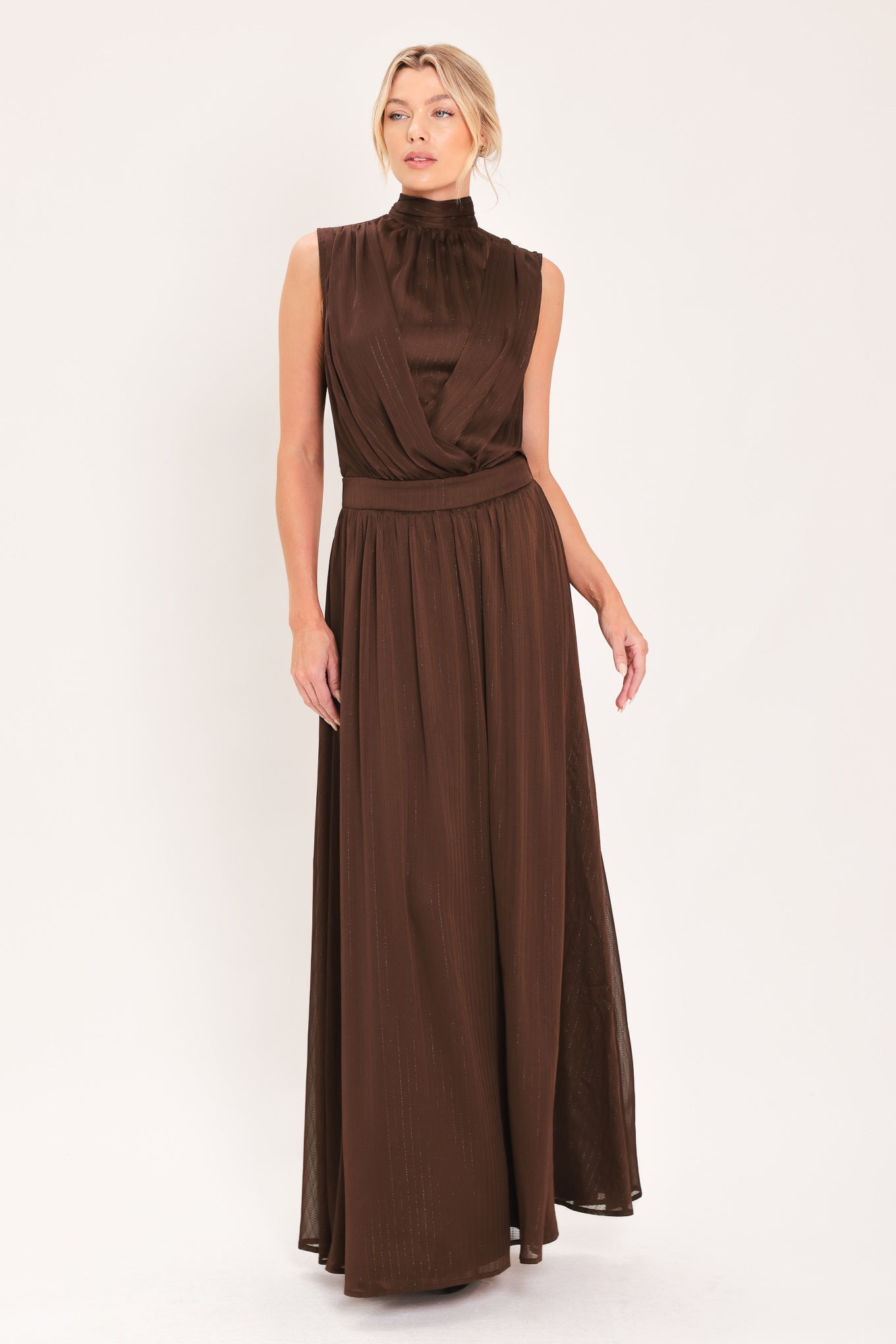A woman modeling a sleeveless, high-neck, maxi brown dress | Flying Tomato