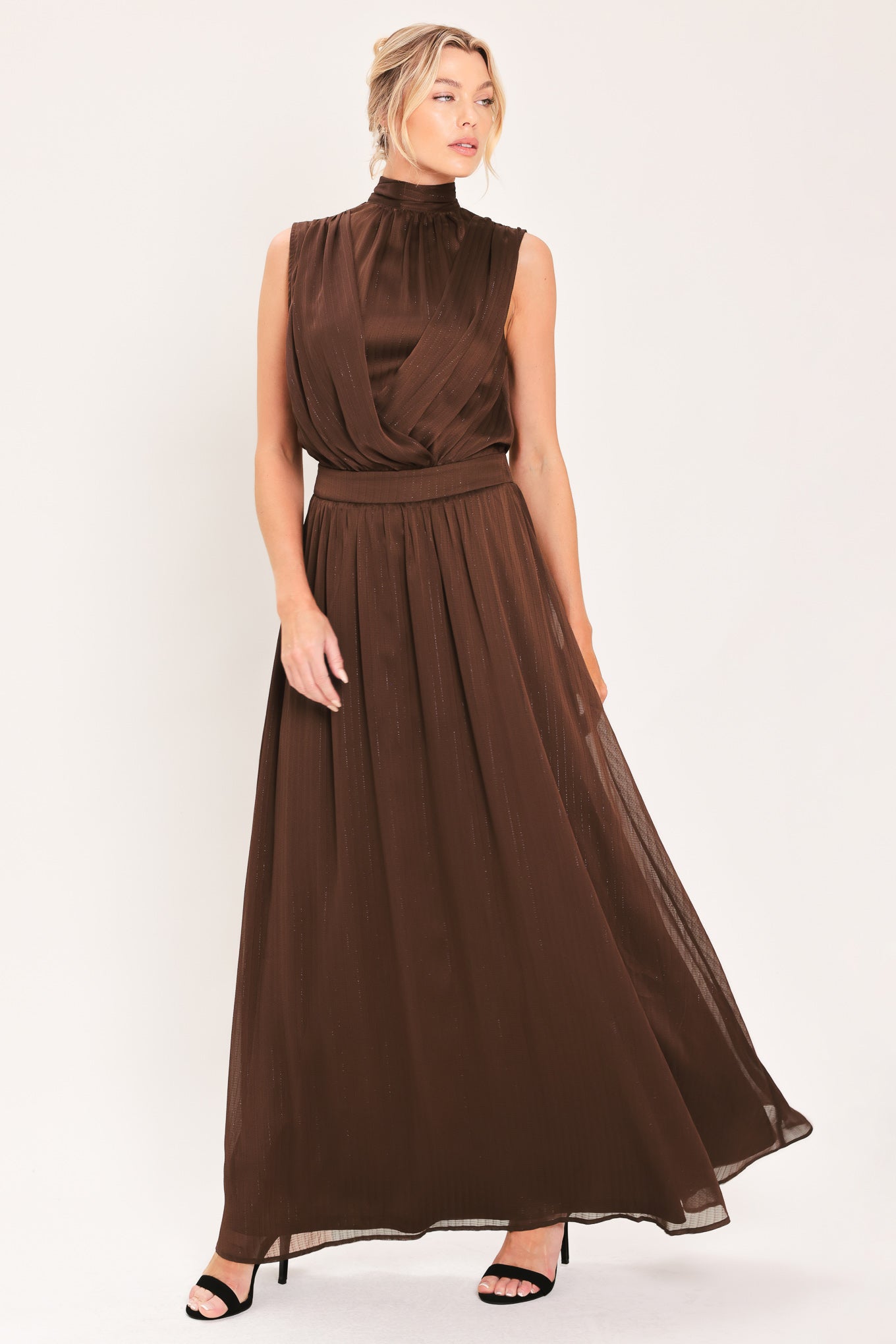 A woman modeling a sleeveless, high-neck, maxi brown dress | Flying Tomato