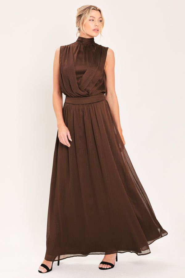 A woman modeling a sleeveless, high-neck, maxi brown dress | Flying Tomato