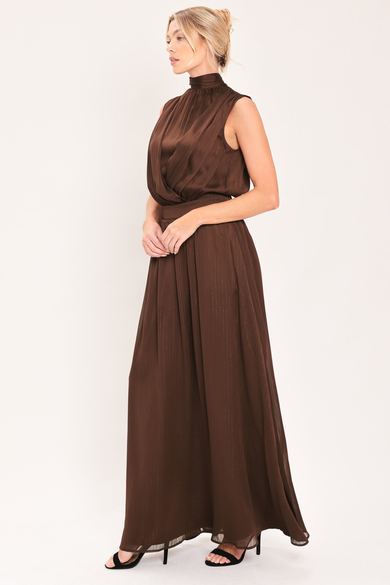 A woman modeling a sleeveless, high-neck, maxi brown dress | Flying Tomato