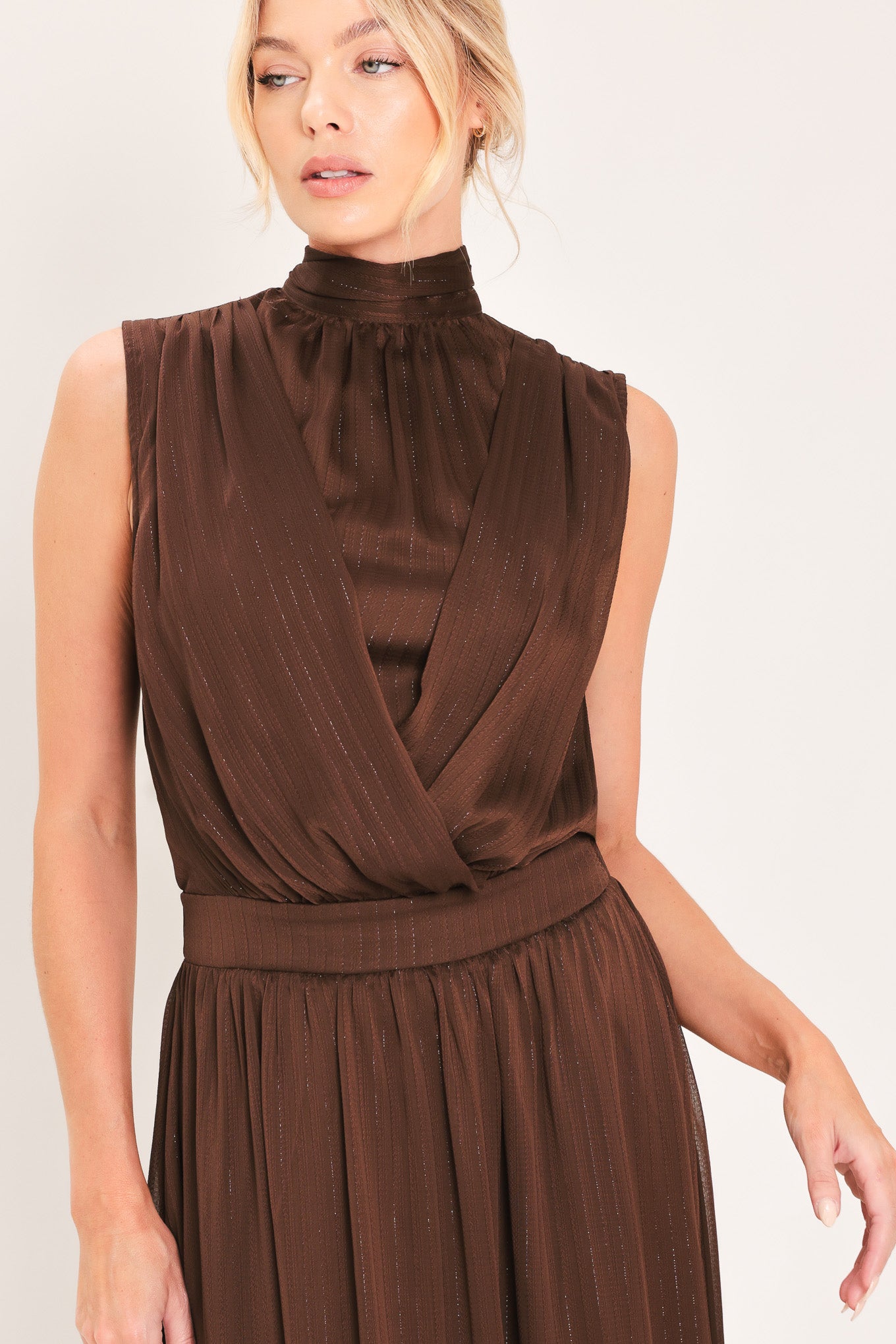 A woman modeling a sleeveless, high-neck, maxi brown dress | Flying Tomato