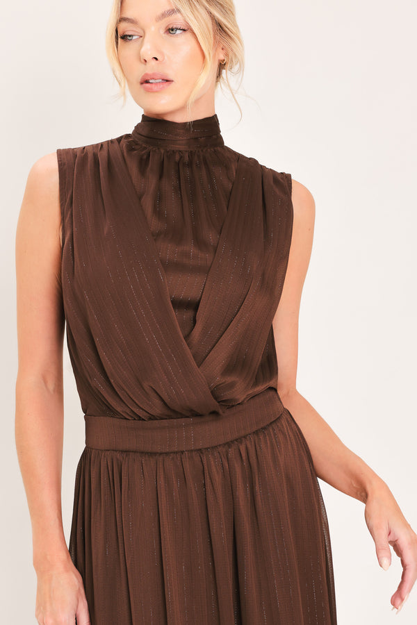 A woman modeling a sleeveless, high-neck, maxi brown dress | Flying Tomato