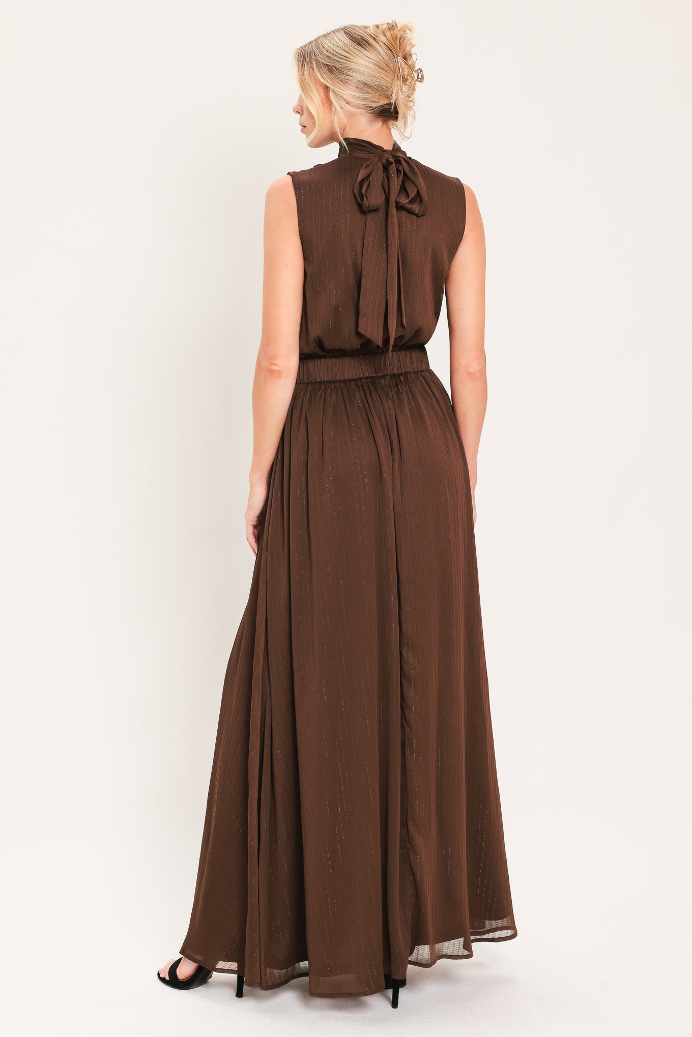 A woman modeling a sleeveless, high-neck, maxi brown dress | Flying Tomato