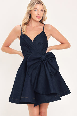 A woman modeling a dark navy blue mini dress with spaghetti straps, a wrap-style bodice, and a large bow detail at the waist | Flying Tomato