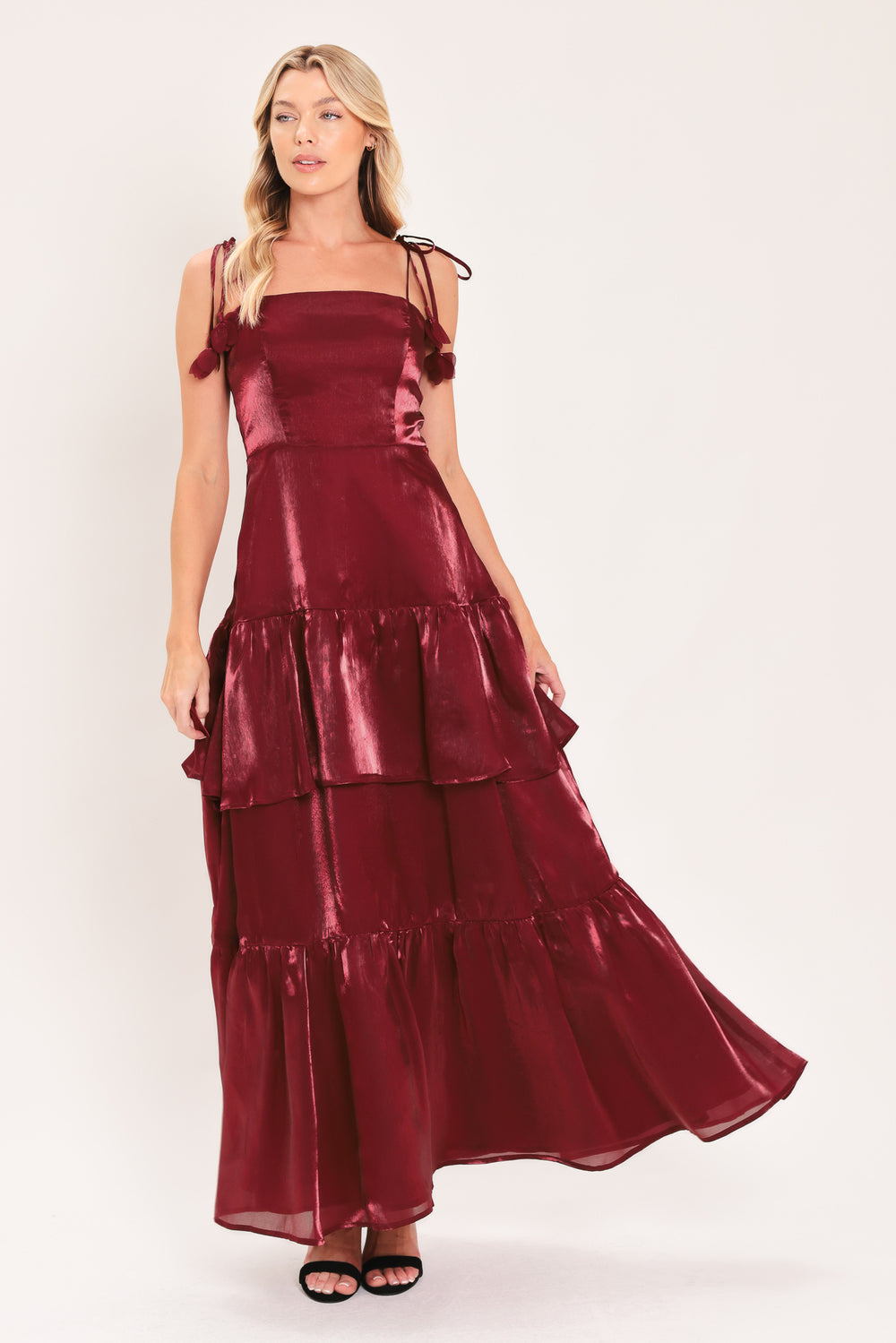 A woman modeling a sleeveless, tiered maxi dress in a shiny deep burgundy or maroon satin-like fabric | Flying Tomato
