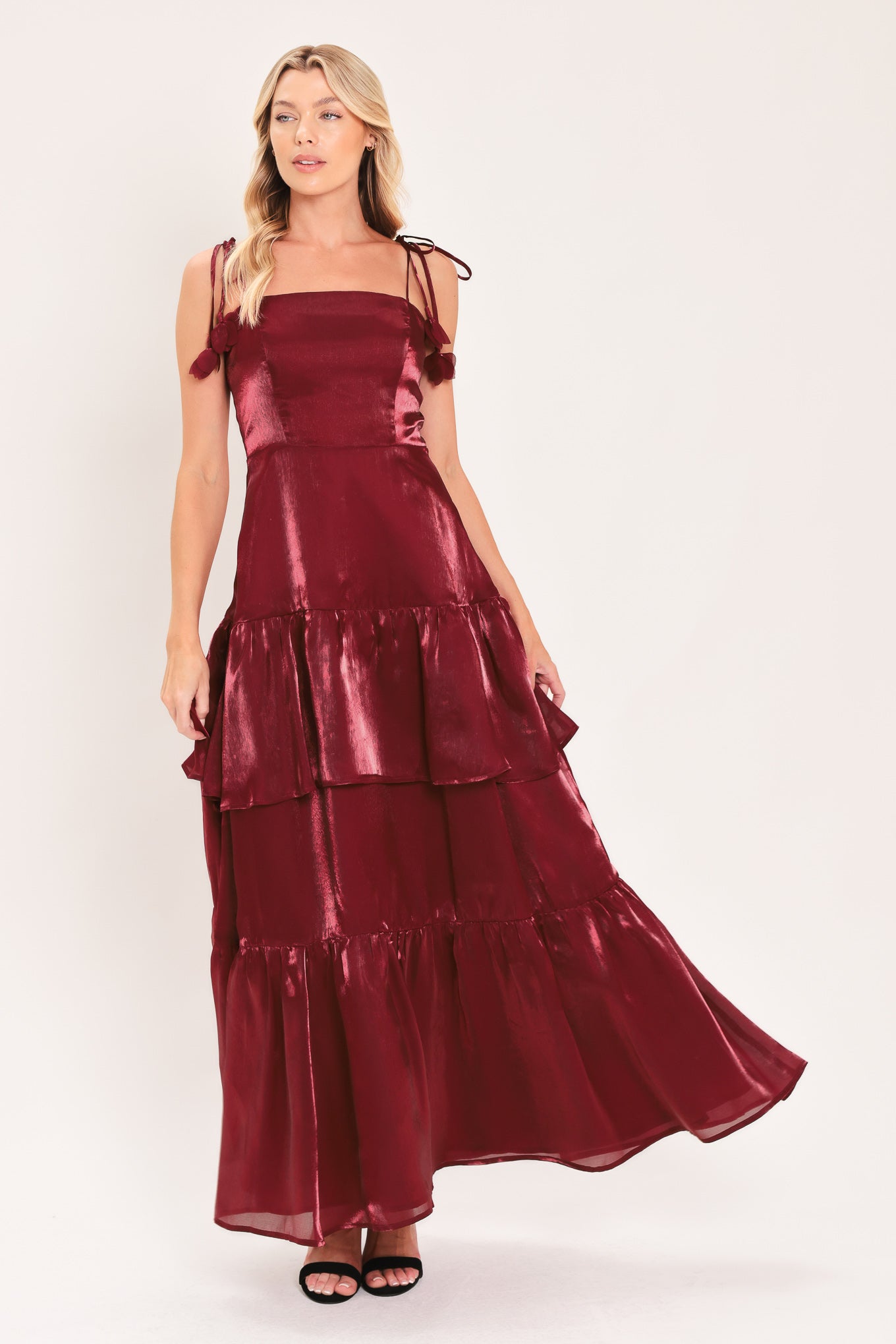 A woman modeling a sleeveless, tiered maxi dress in a shiny deep burgundy or maroon satin-like fabric | Flying Tomato
