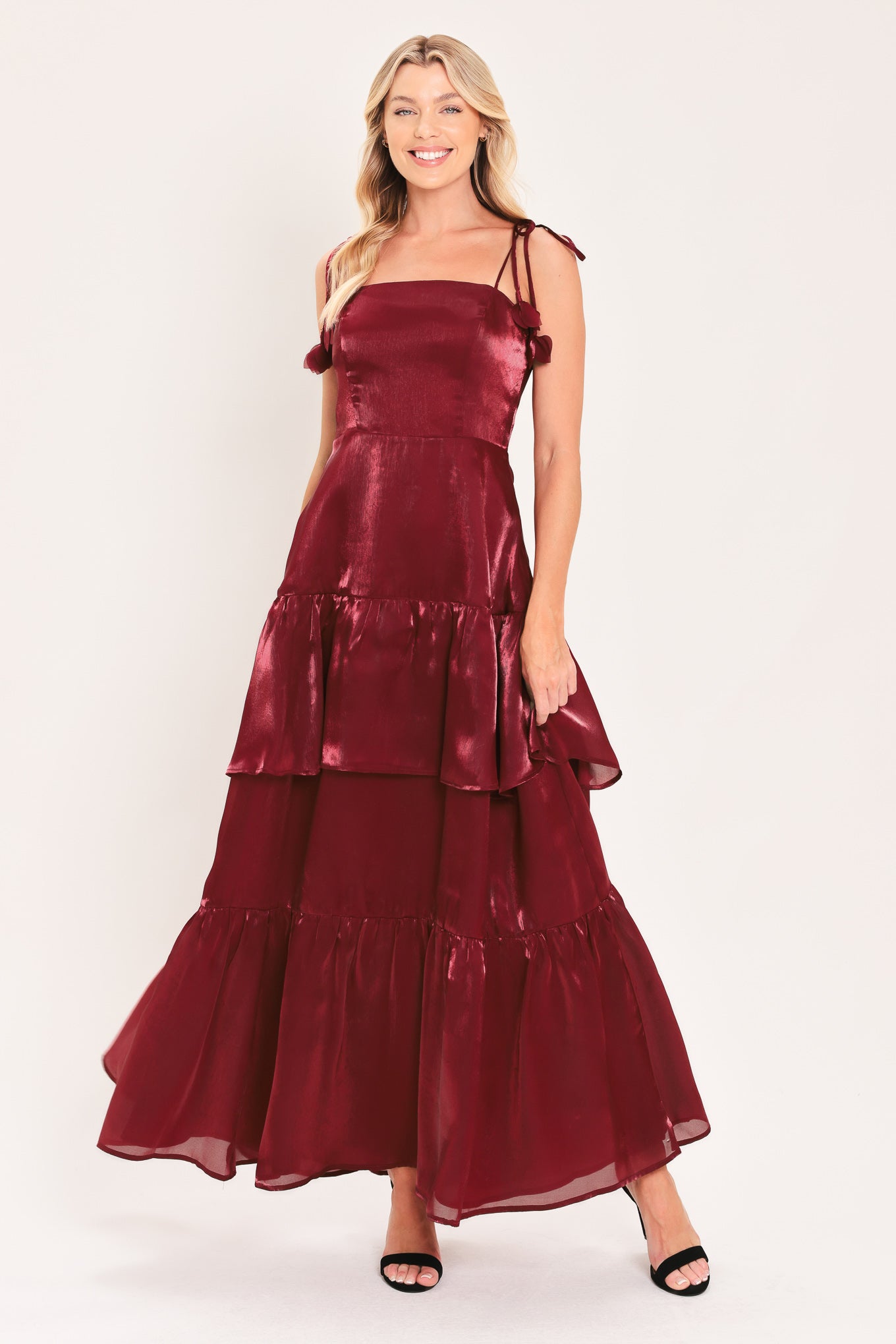 A woman modeling a sleeveless, tiered maxi dress in a shiny deep burgundy or maroon satin-like fabric | Flying Tomato