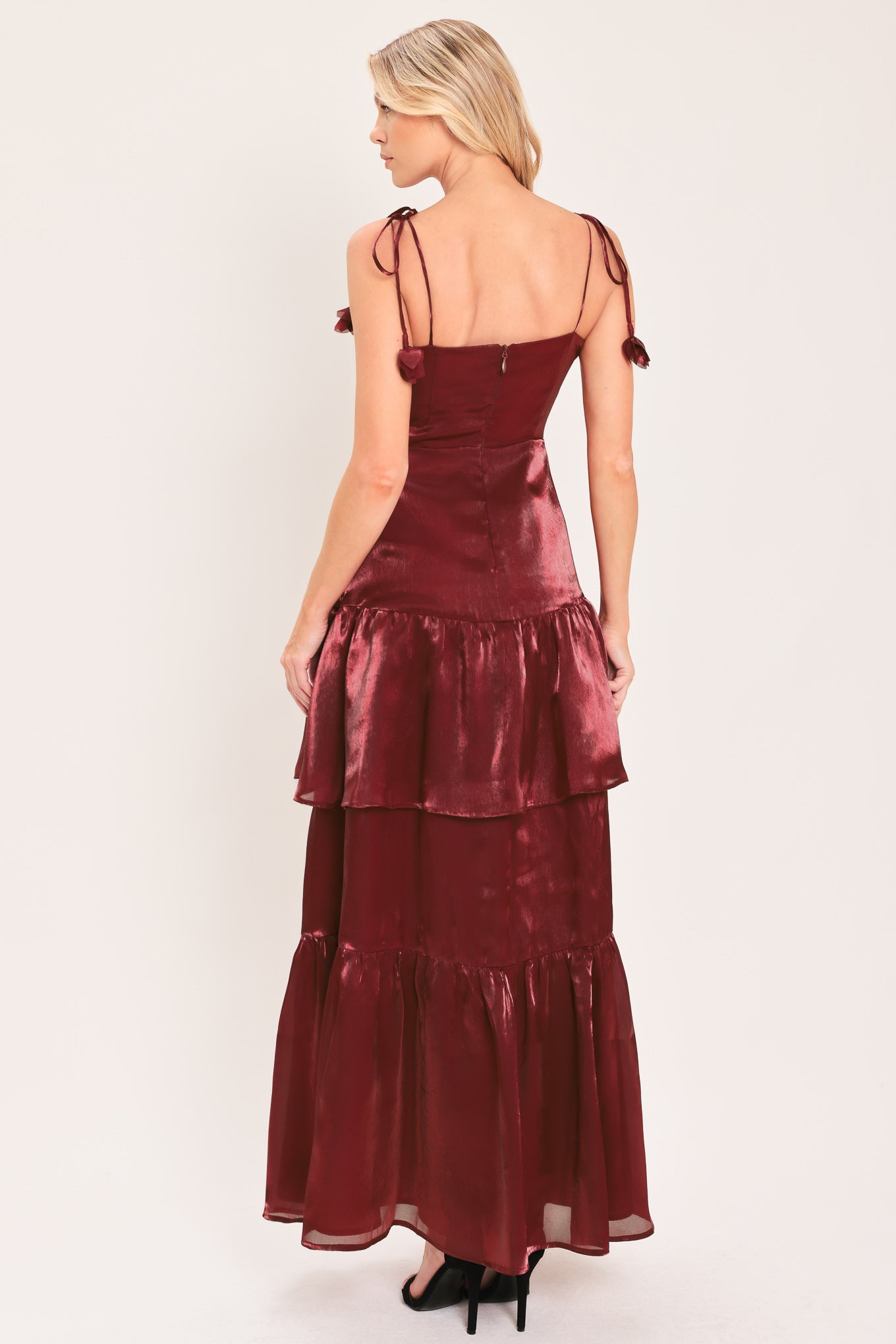 A woman modeling a sleeveless, tiered maxi dress in a shiny deep burgundy or maroon satin-like fabric | Flying Tomato
