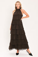 A woman modeling a sleeveless, high-neck, tiered maxi dress in a dark brown color | Flying Tomato