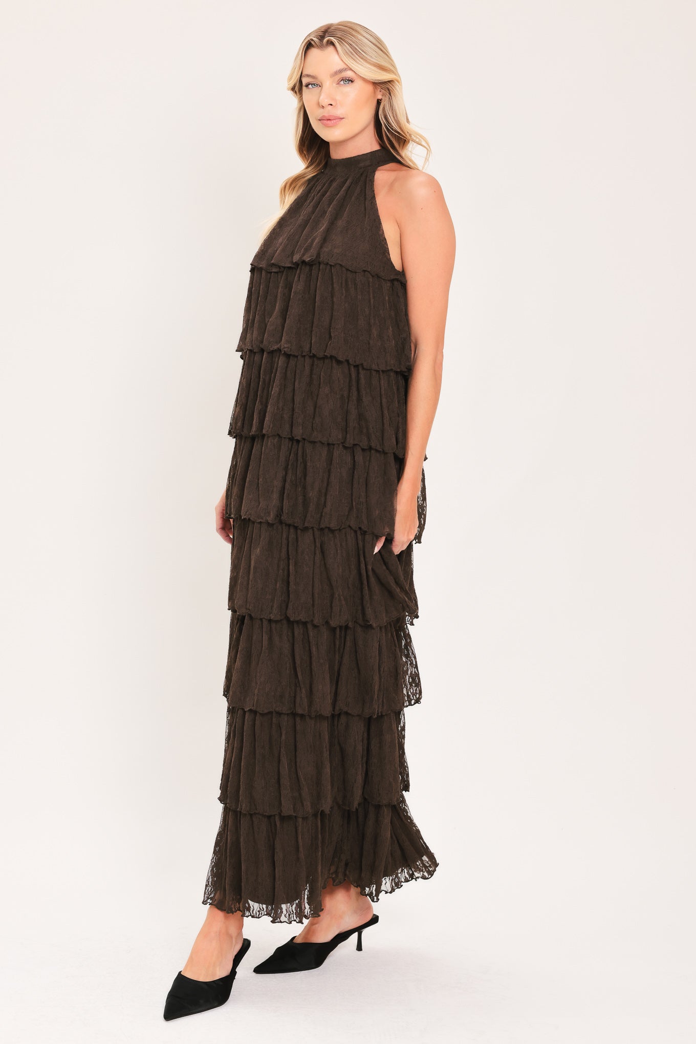 A woman modeling a sleeveless, high-neck, tiered maxi dress in a dark brown color | Flying Tomato