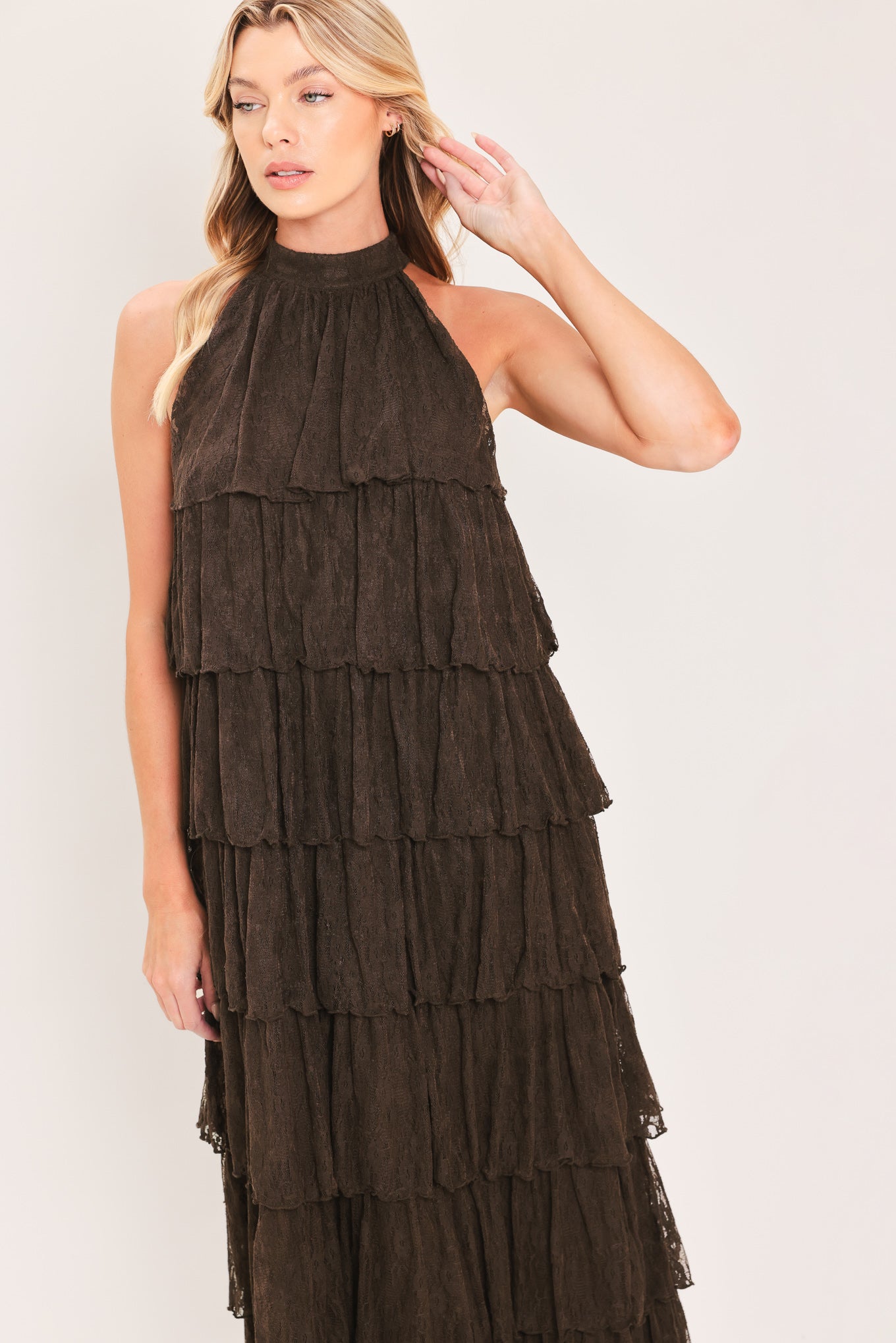 A woman modeling a sleeveless, high-neck, tiered maxi dress in a dark brown color | Flying Tomato