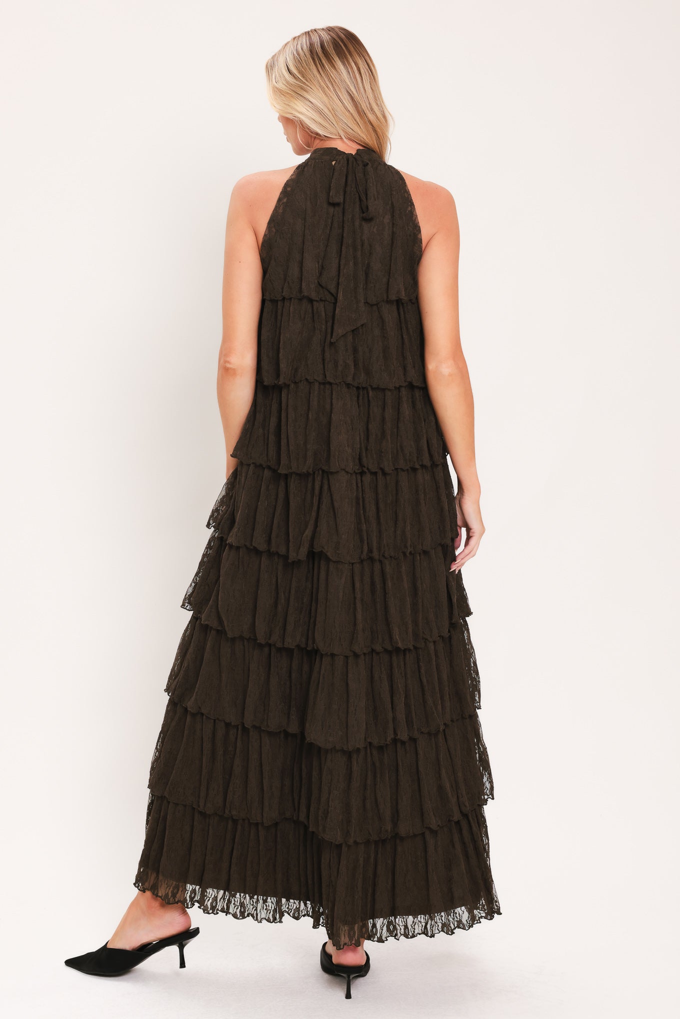 A woman modeling a sleeveless, high-neck, tiered maxi dress in a dark brown color | Flying Tomato