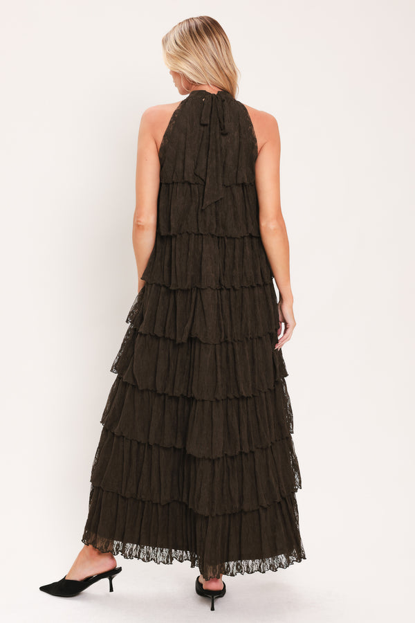 A woman modeling a sleeveless, high-neck, tiered maxi dress in a dark brown color | Flying Tomato