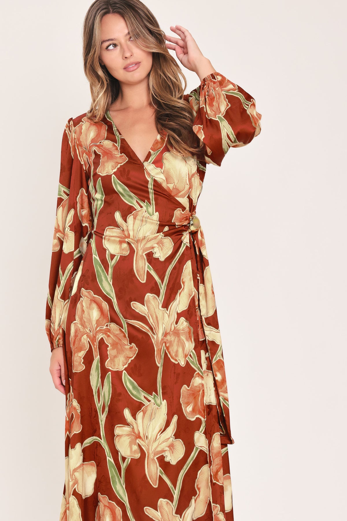A woman modeling a long-sleeve midi wrap dress with a brown, beige, and green floral pattern | Flying Tomato