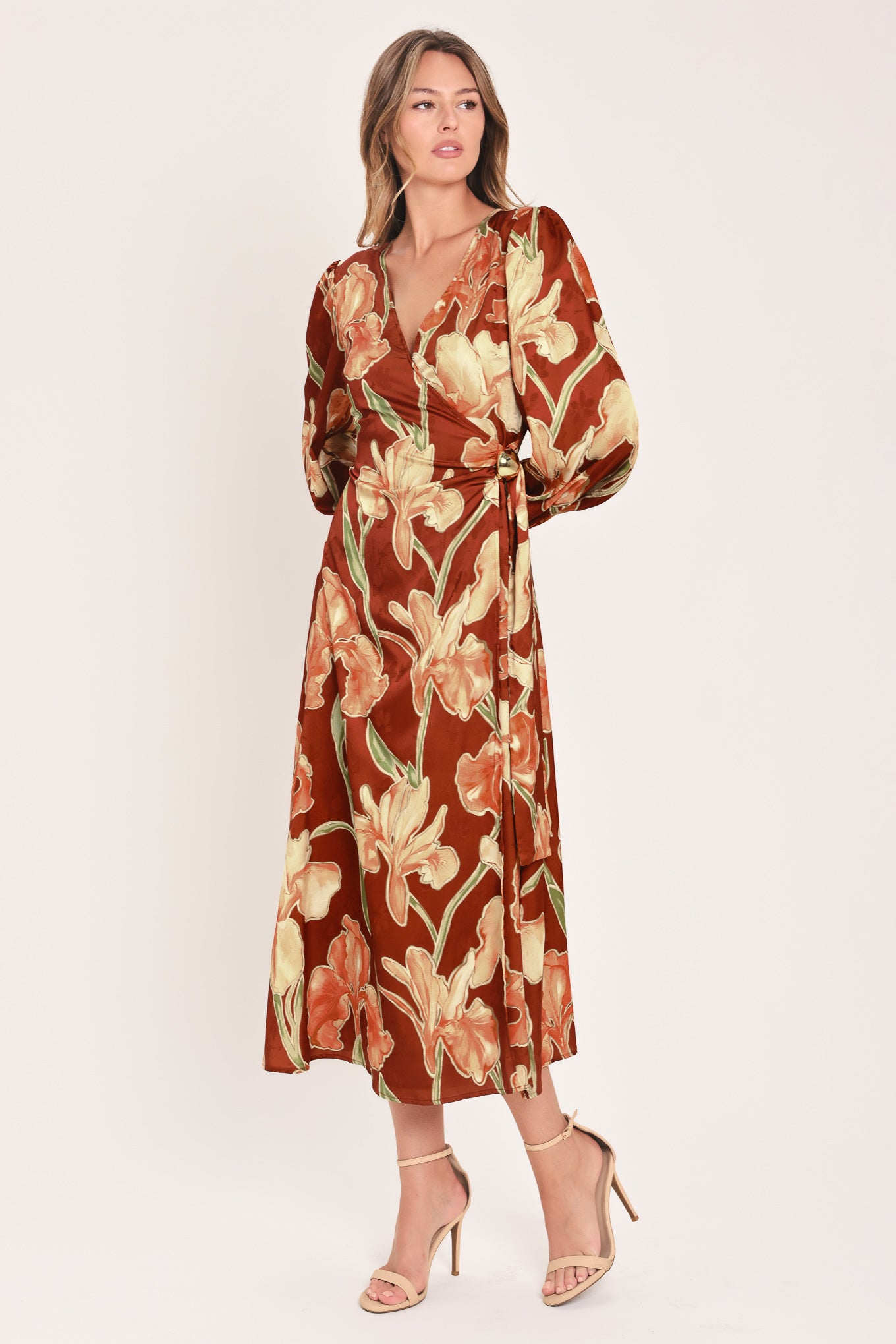 A woman modeling a long-sleeve midi wrap dress with a brown, beige, and green floral pattern | Flying Tomato